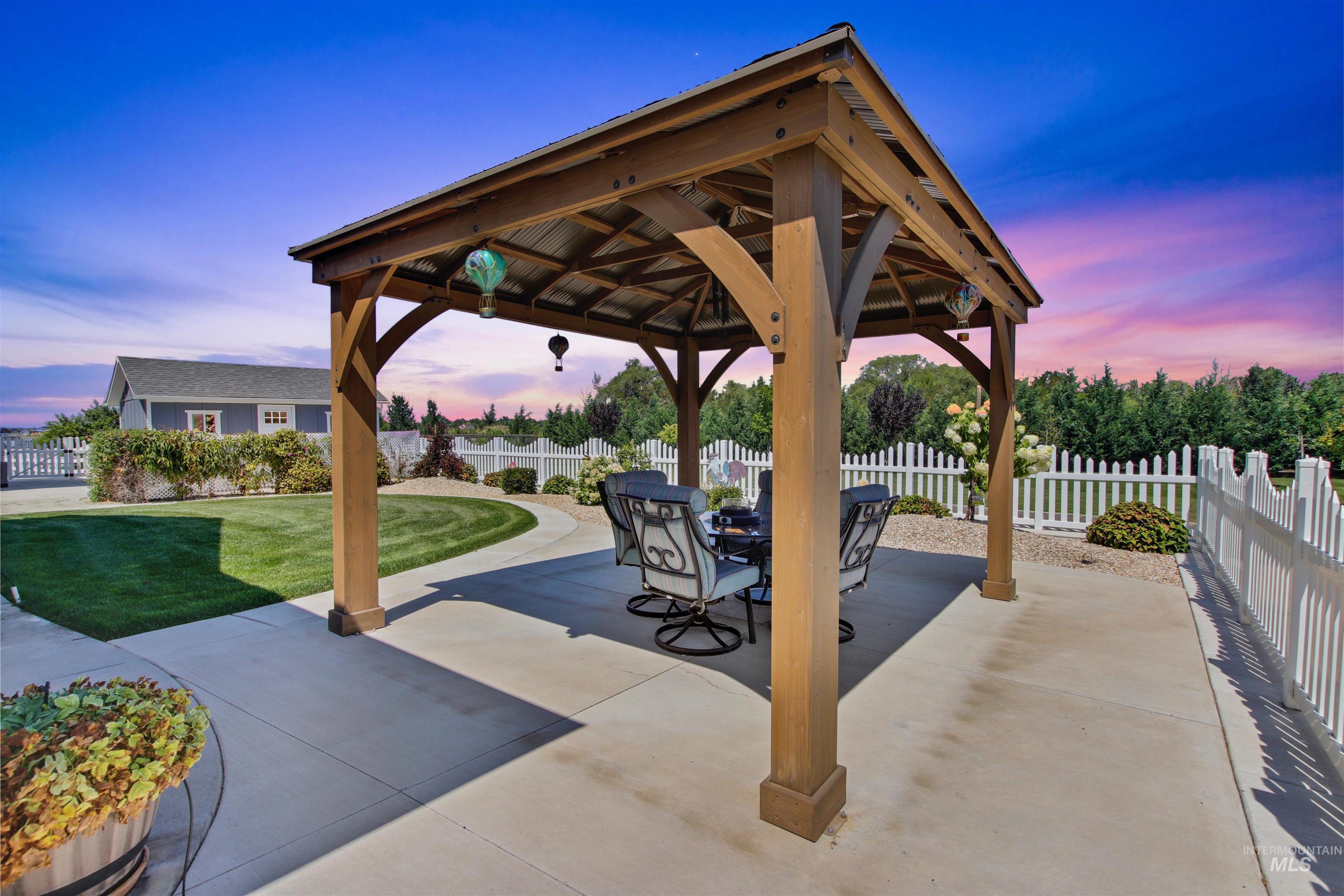 Patio terrace at dusk with a patio area, a fenced backyard, a gazebo, and outdoor dining area