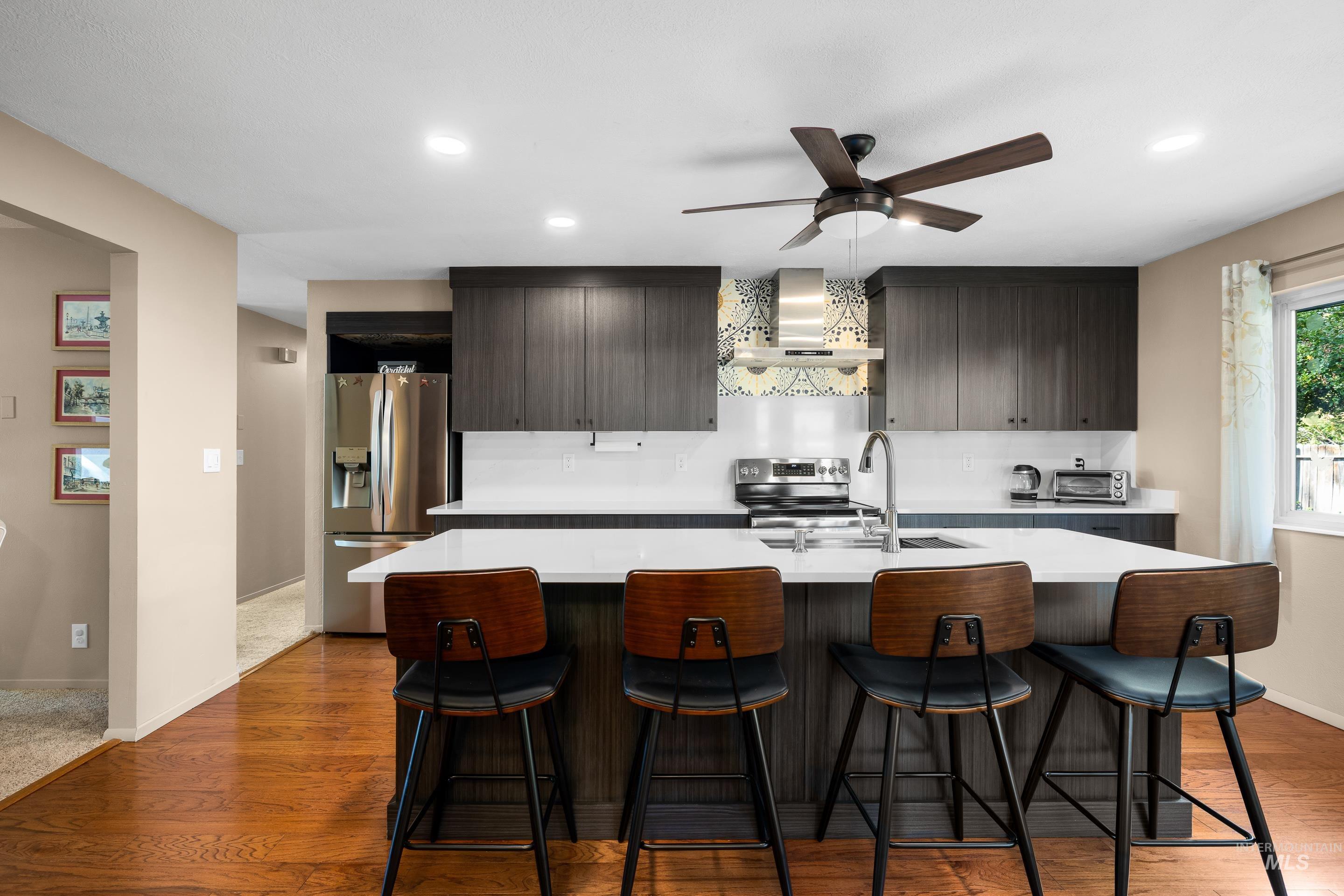 Kitchen featuring modern cabinets, an island with sink, dark brown cabinetry, a breakfast bar, and stainless steel appliances