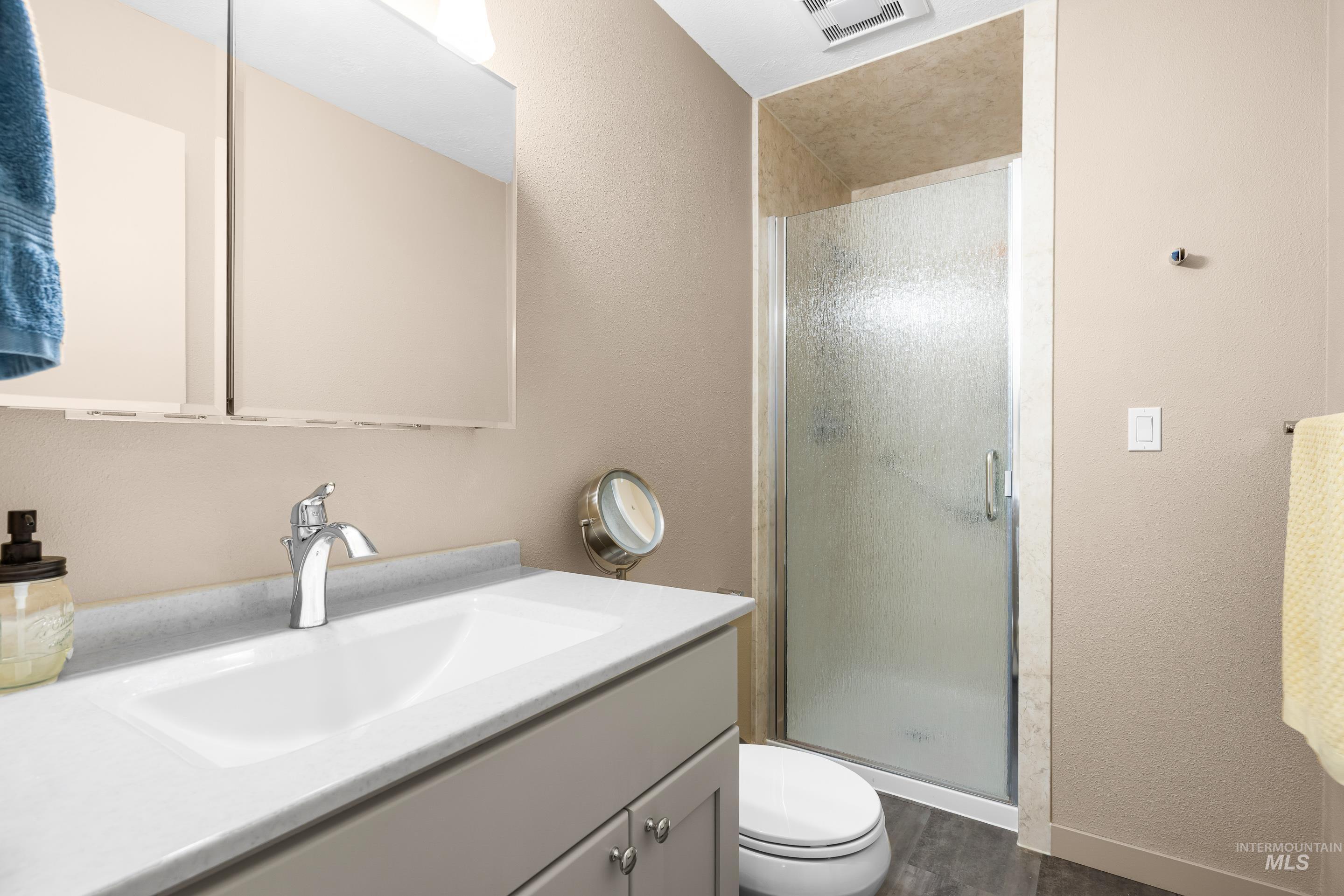 Bathroom featuring vanity, a stall shower, dark wood finished floors, and a textured wall