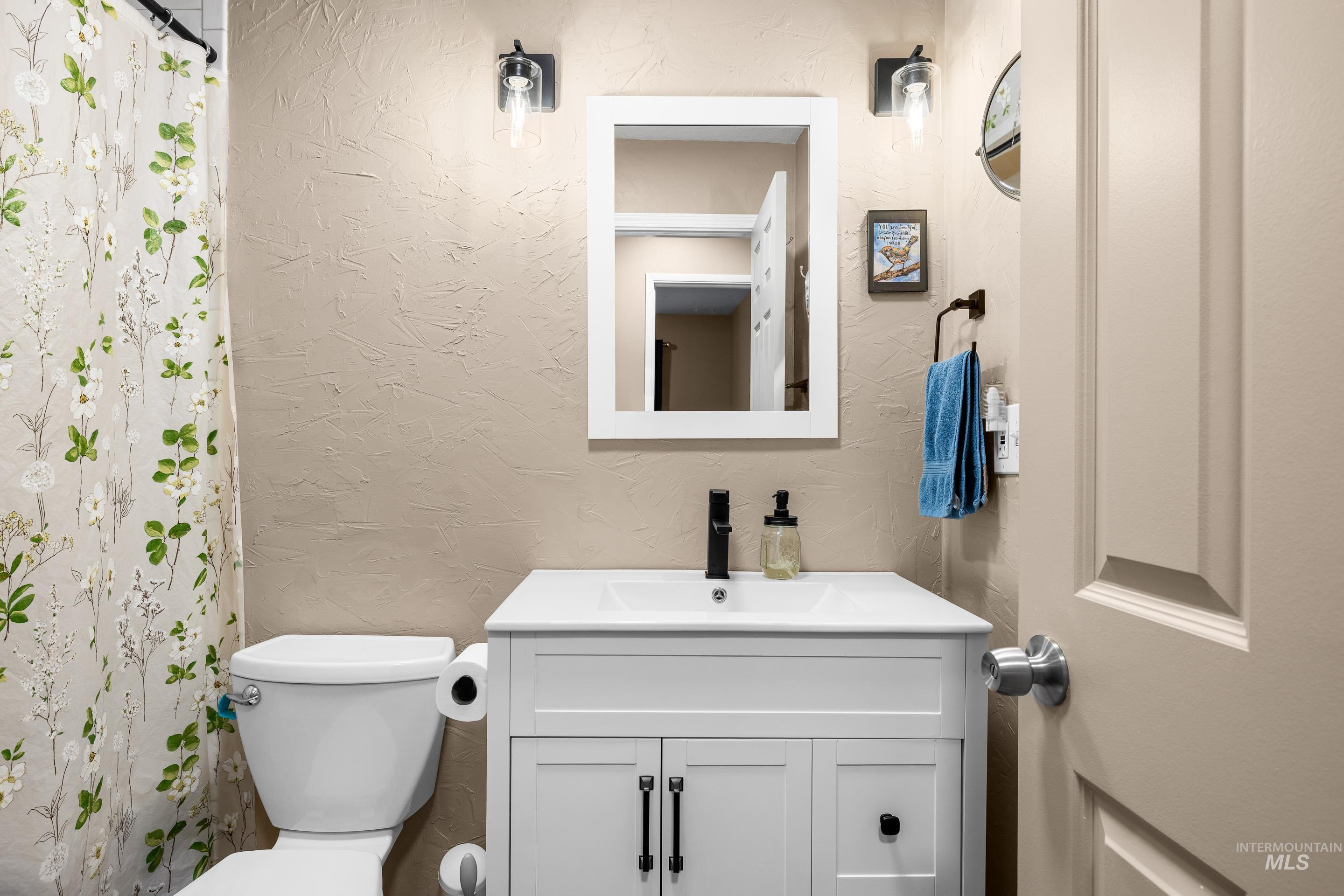 Bathroom with a textured wall, vanity, and a shower with shower curtain