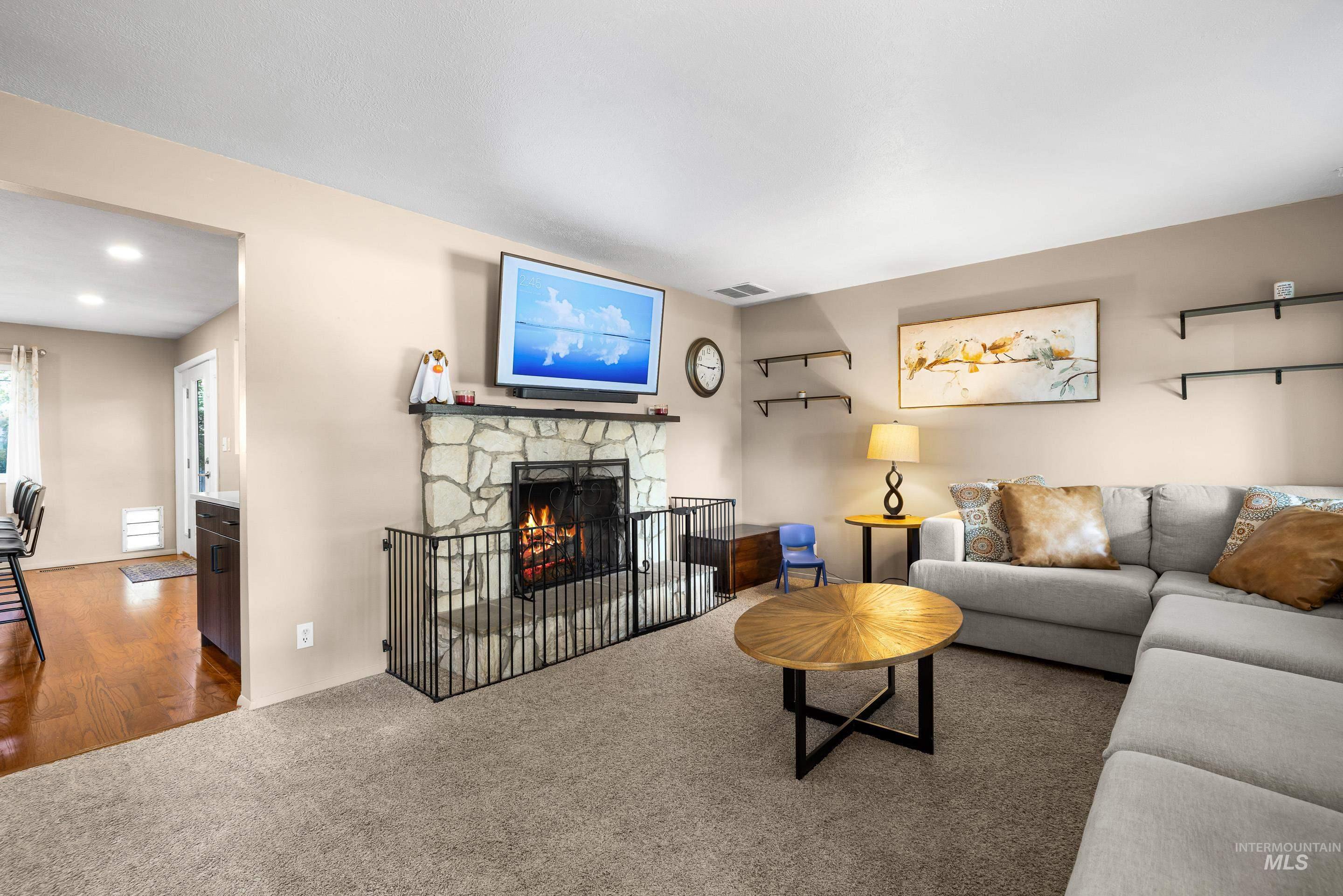 Living room featuring a stone fireplace and carpet