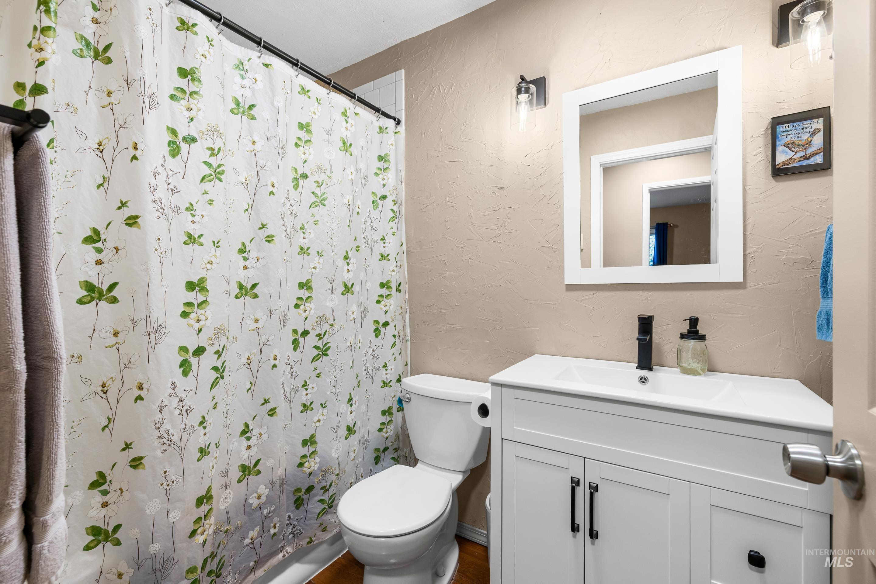 Bathroom featuring a textured wall, vanity, and a shower with shower curtain