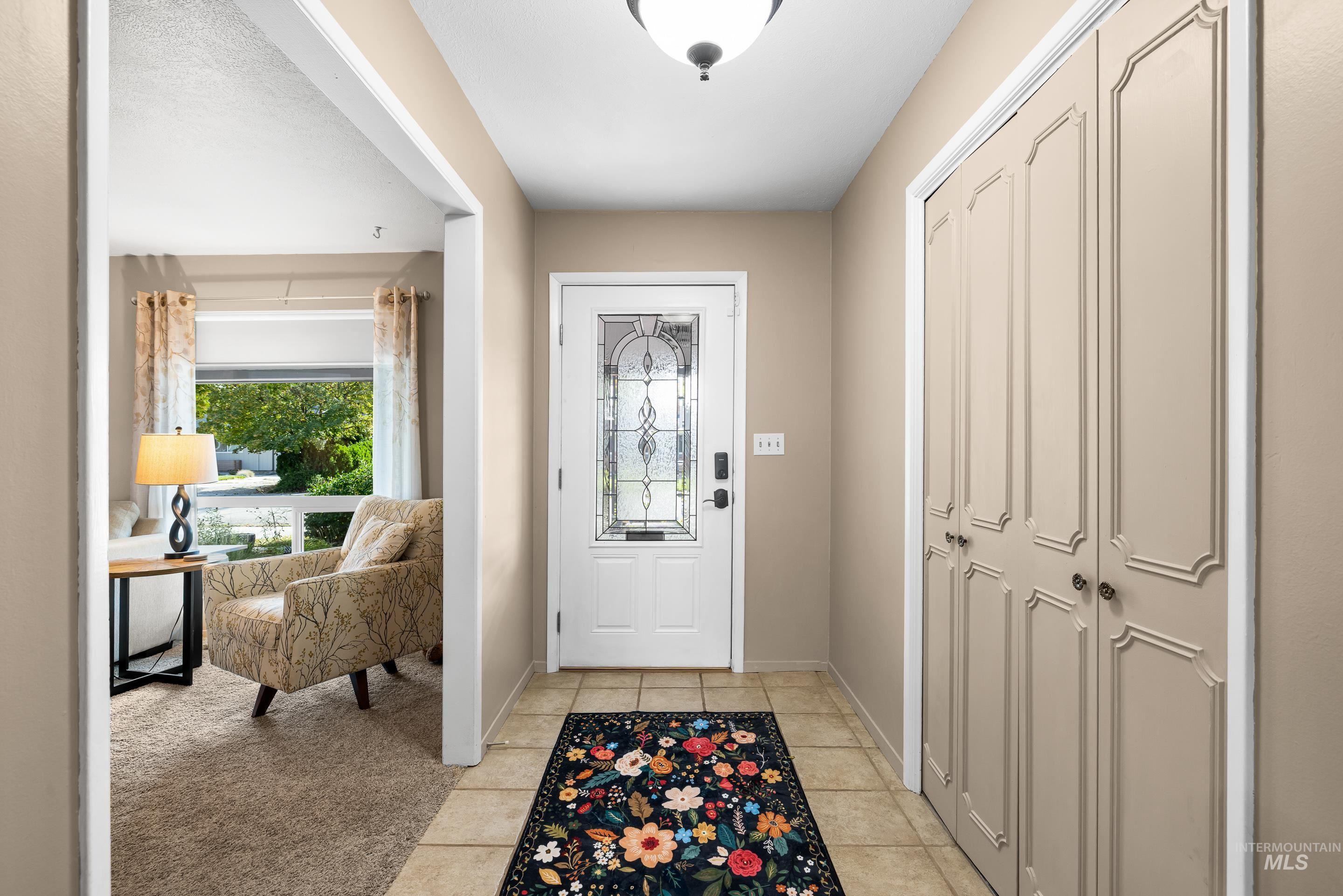 Foyer with light tile patterned floors and light carpet