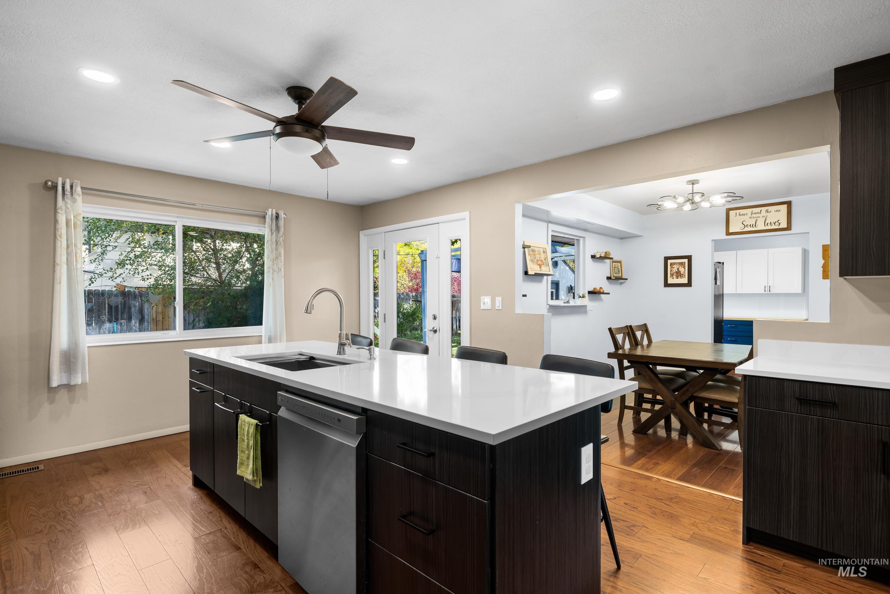 Kitchen featuring a breakfast bar, dark wood finished floors, stainless steel dishwasher, an island with sink, and recessed lighting