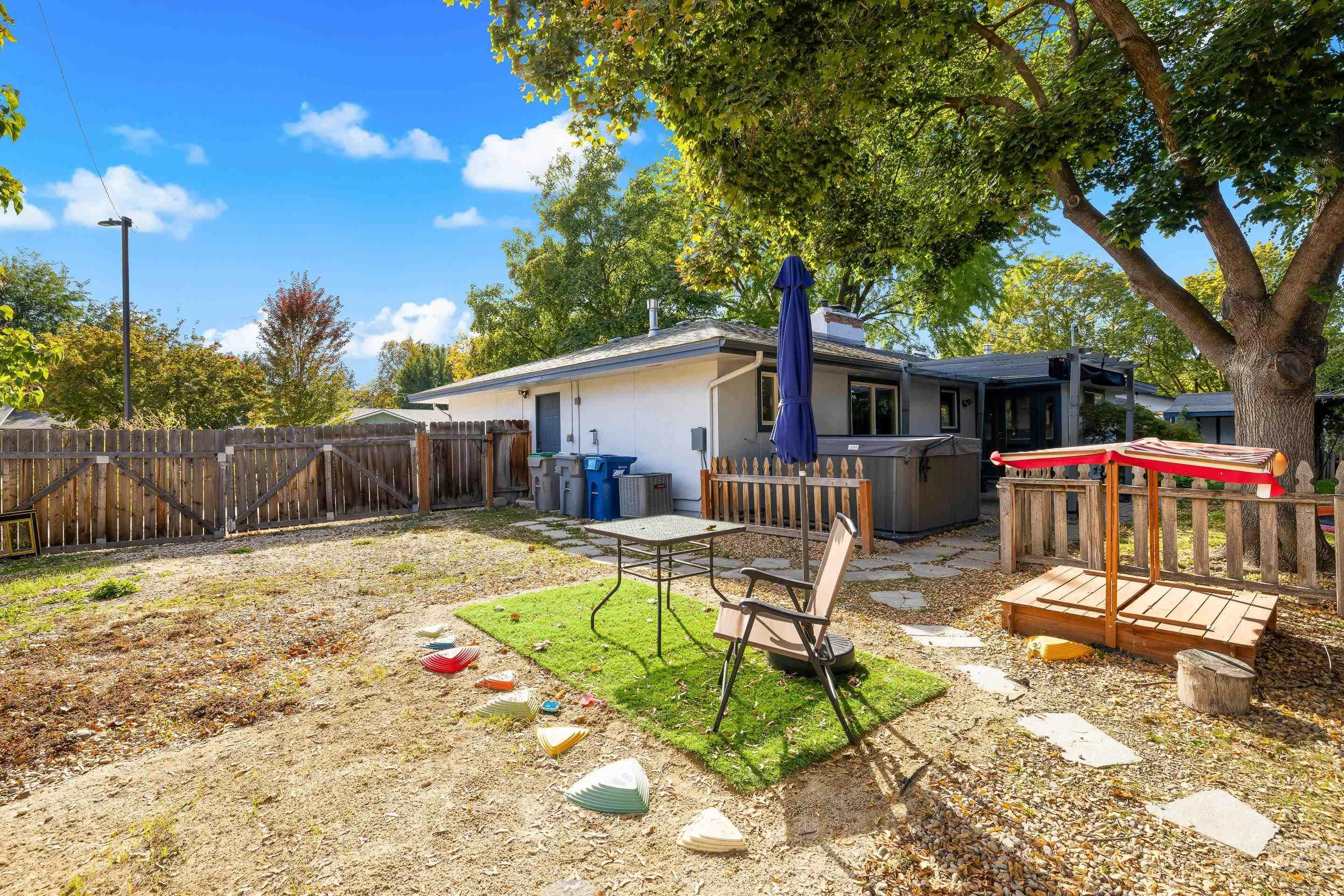 Rear view of property with a deck, stucco siding, a hot tub, and a fenced backyard