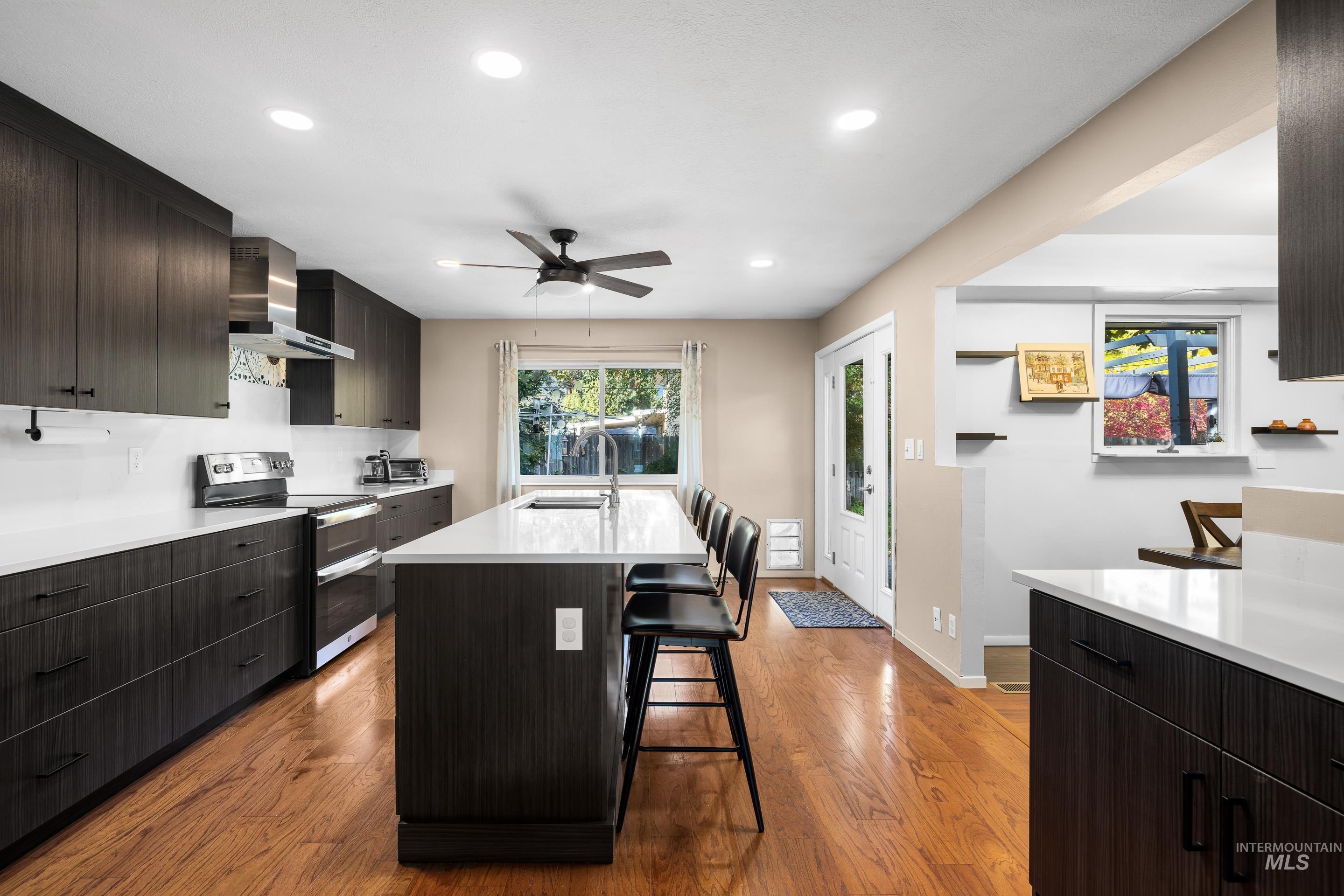 Kitchen with modern cabinets, double oven range, dark brown cabinetry, recessed lighting, and a kitchen bar