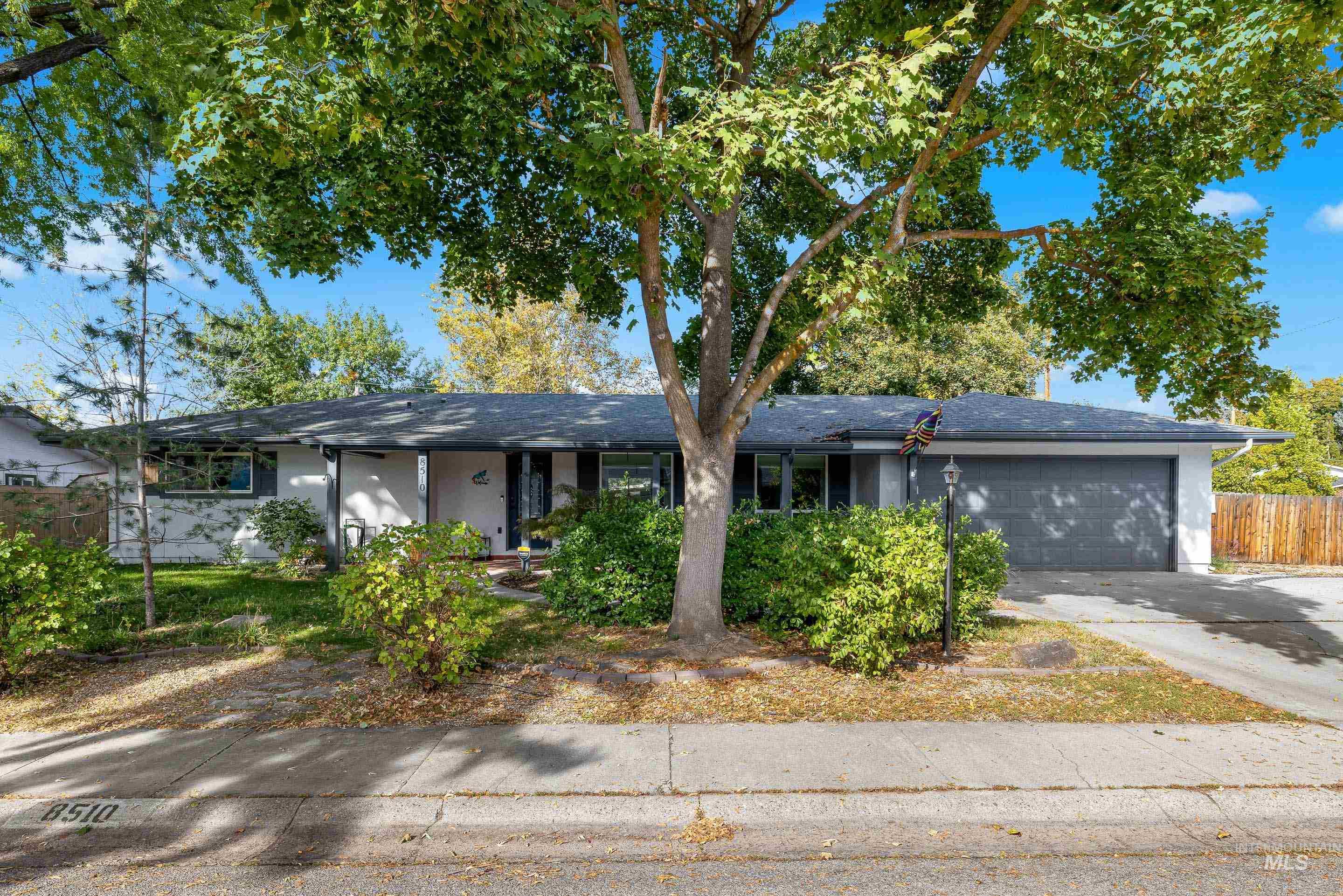 Ranch-style house with a garage, concrete driveway, roof with shingles, and a porch