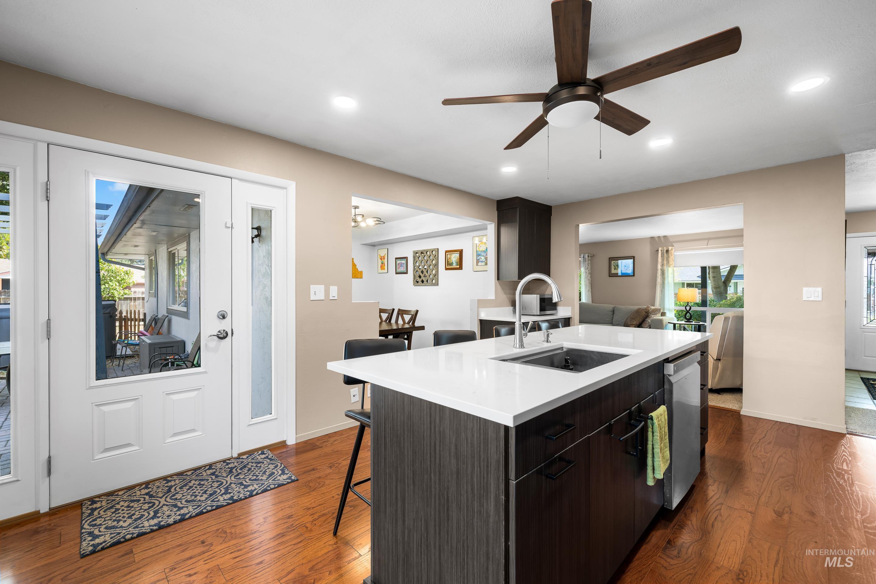 Kitchen with a kitchen bar, dark wood-style floors, modern cabinets, a center island with sink, and recessed lighting