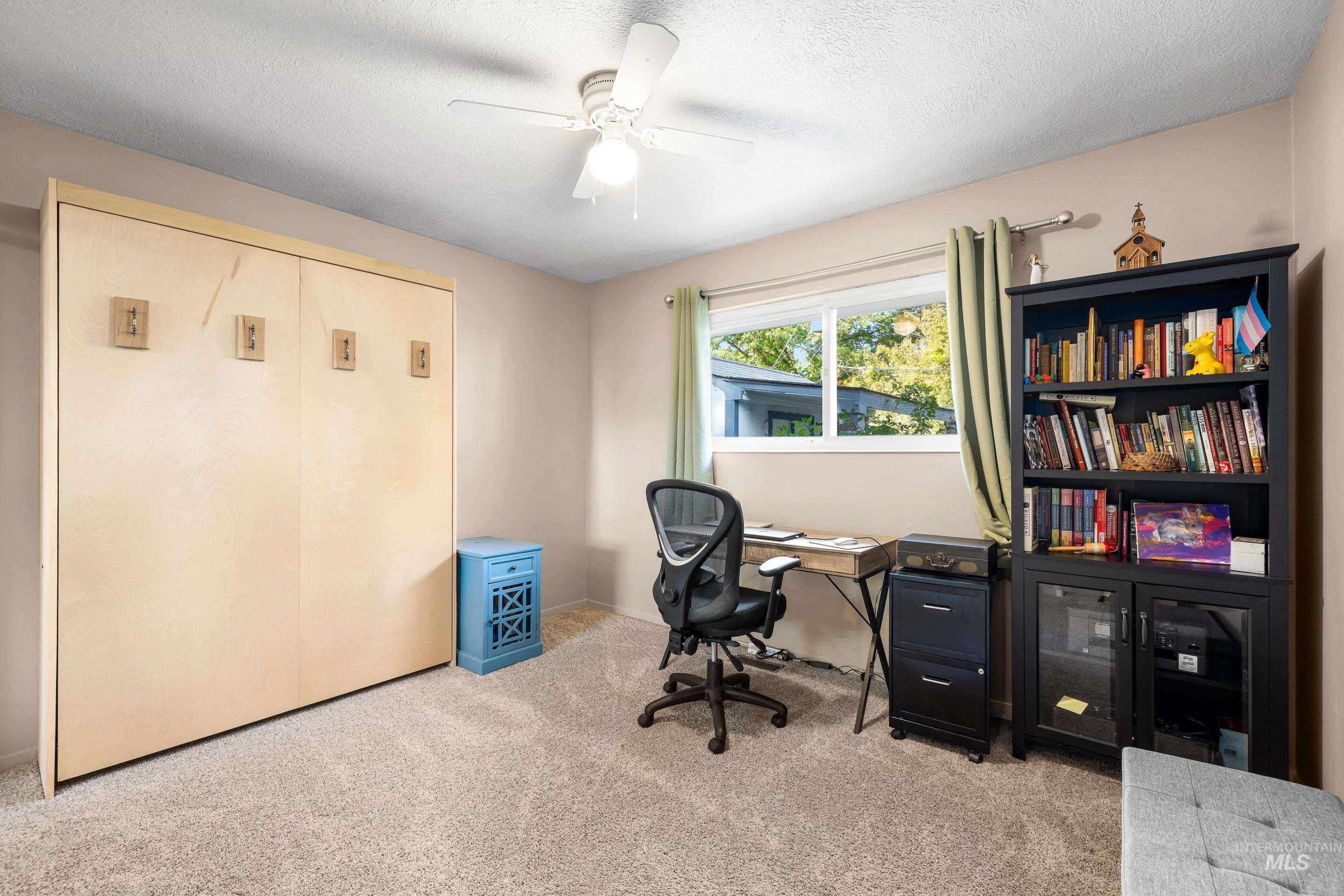 Office featuring light colored carpet, ceiling fan, and a textured ceiling