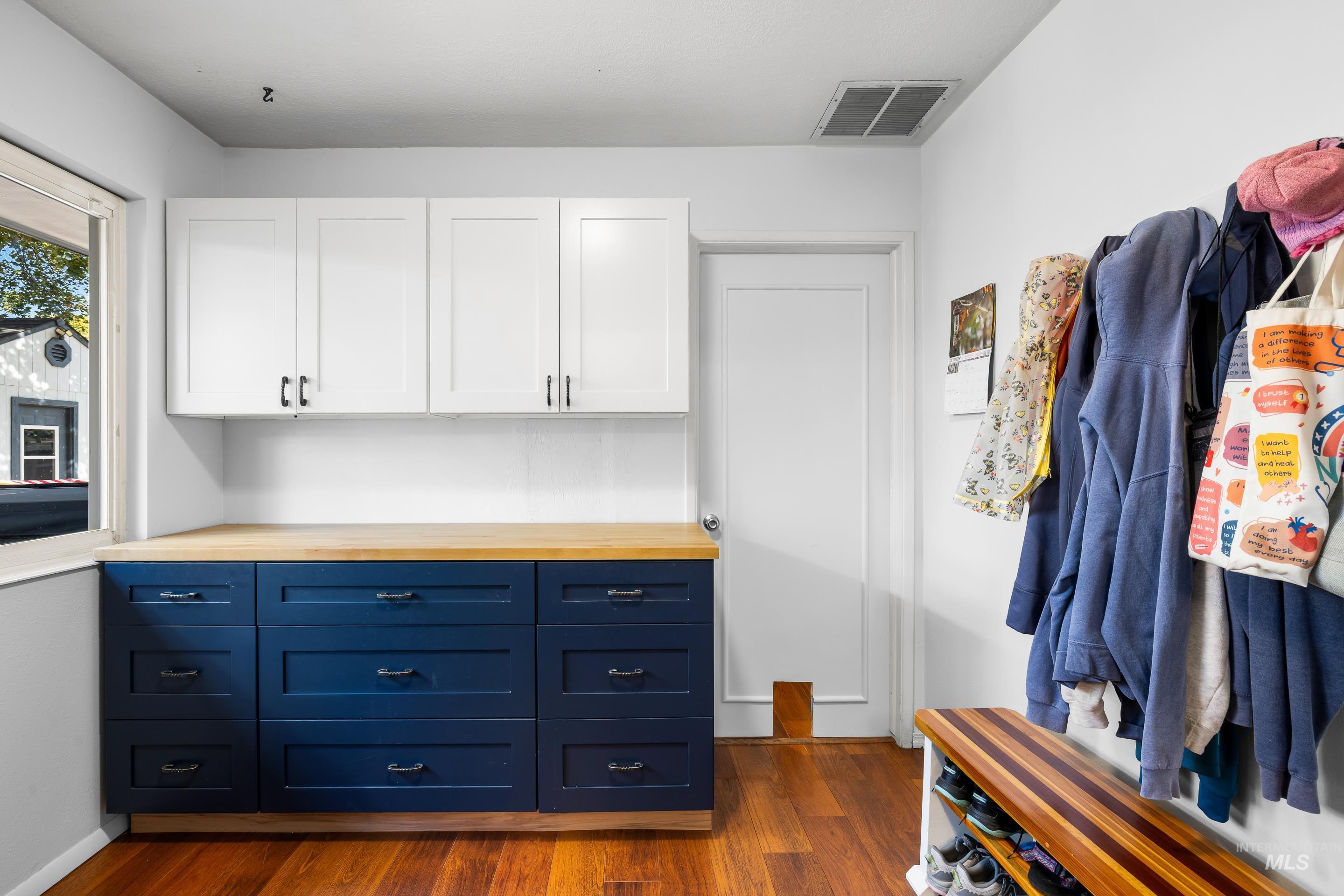 Kitchen featuring blue cabinets, wood counters, white cabinets, and dark wood-type flooring