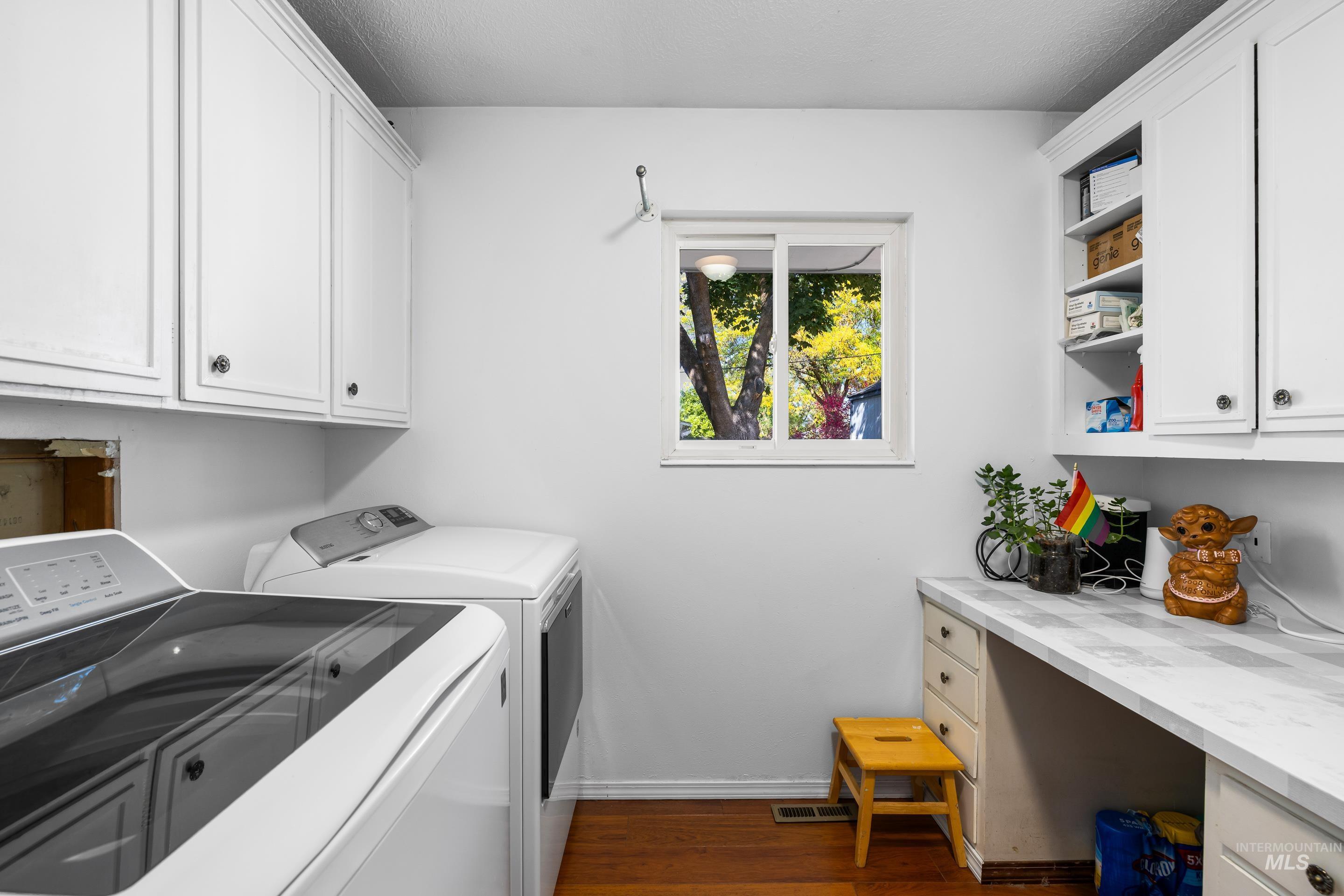 Washroom featuring cabinet space, dark wood-type flooring, and washing machine and dryer