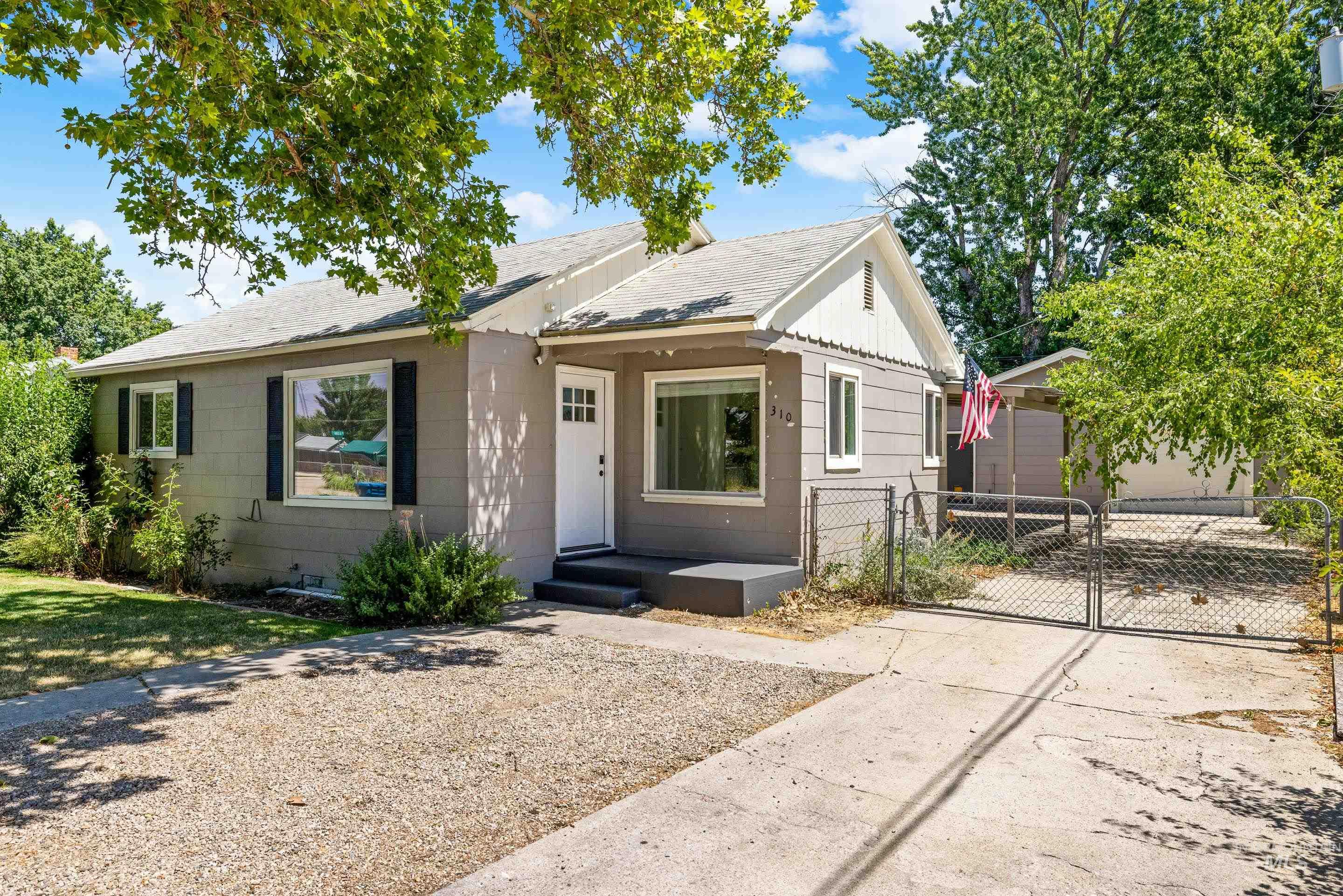 View of front of home featuring roof with shingles, a gate, and an outdoor structure