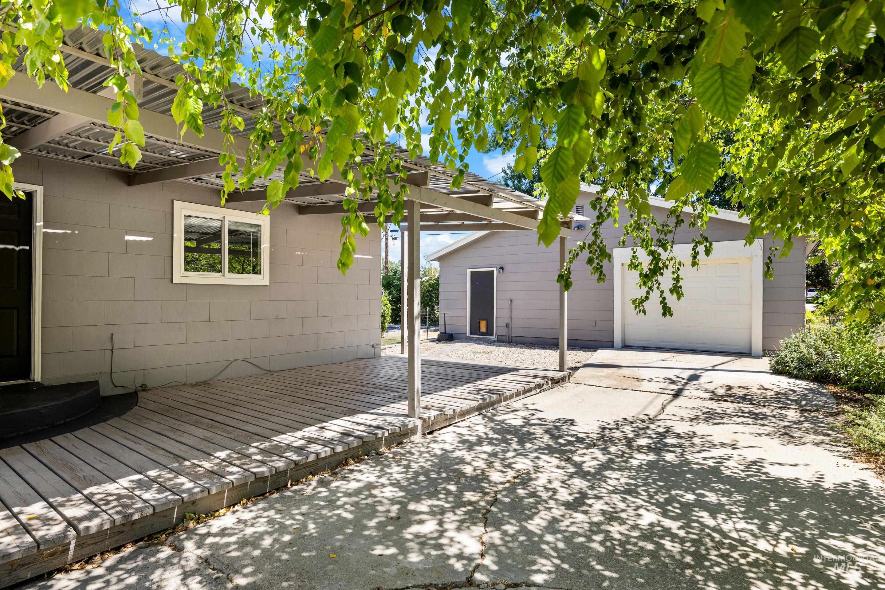 View of patio featuring a garage, an outbuilding, and a wooden deck