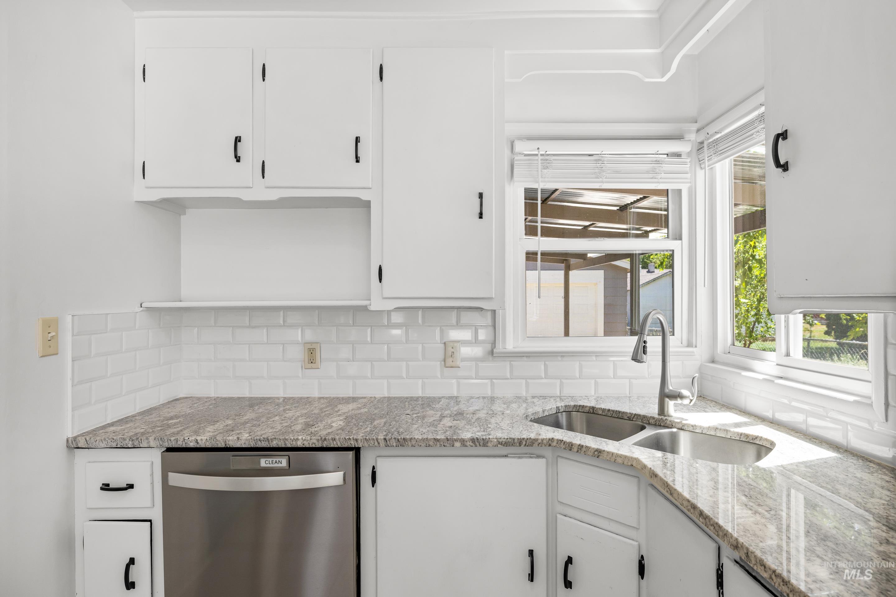 Kitchen with dishwasher, white cabinetry, and tasteful backsplash