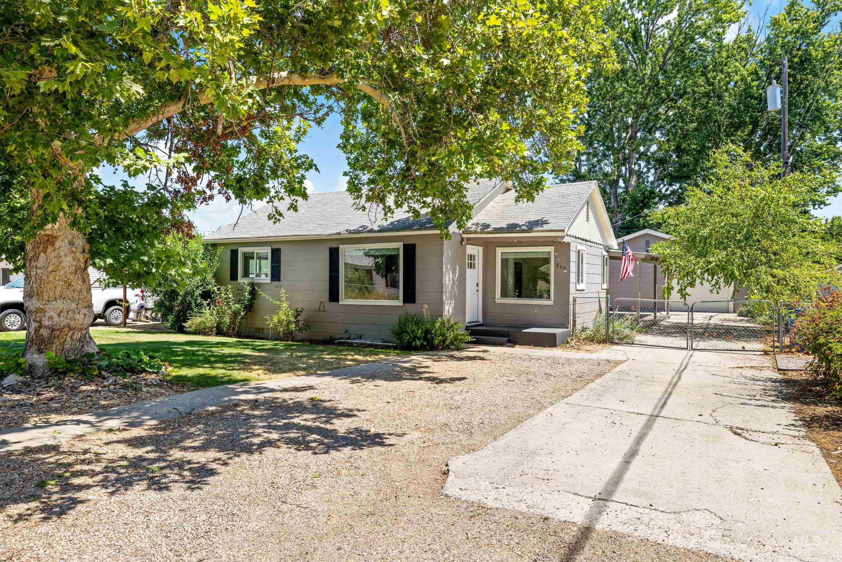 View of front of house featuring a shingled roof, a gate, and driveway