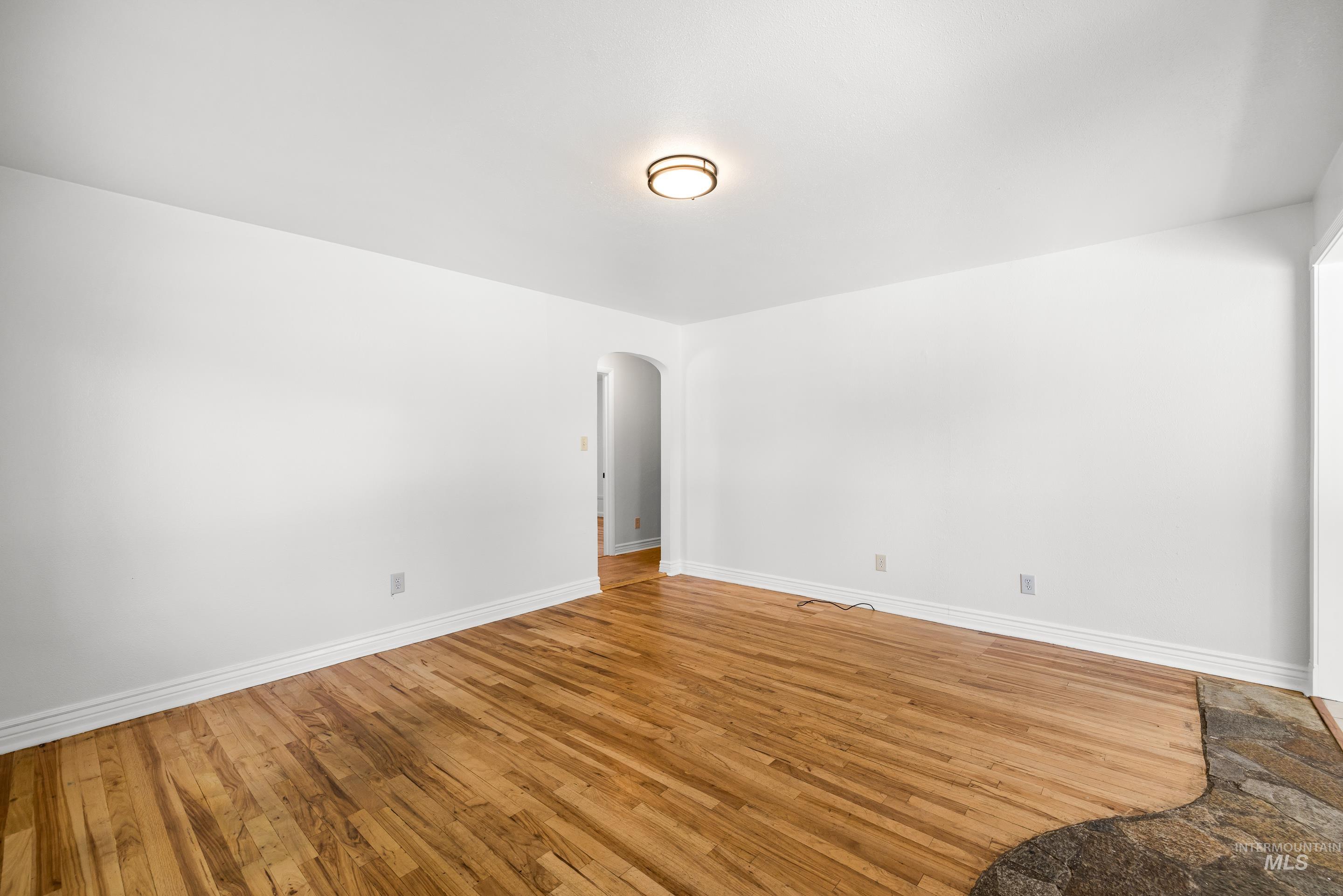 Empty room with arched walkways and wood finished floors