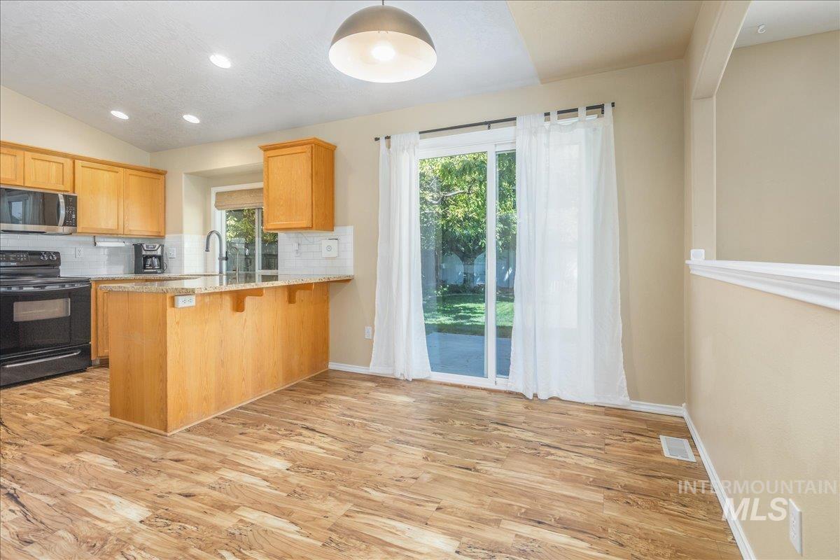 Kitchen featuring black electric range oven, tasteful backsplash, light wood-type flooring, stainless steel microwave, and recessed lighting