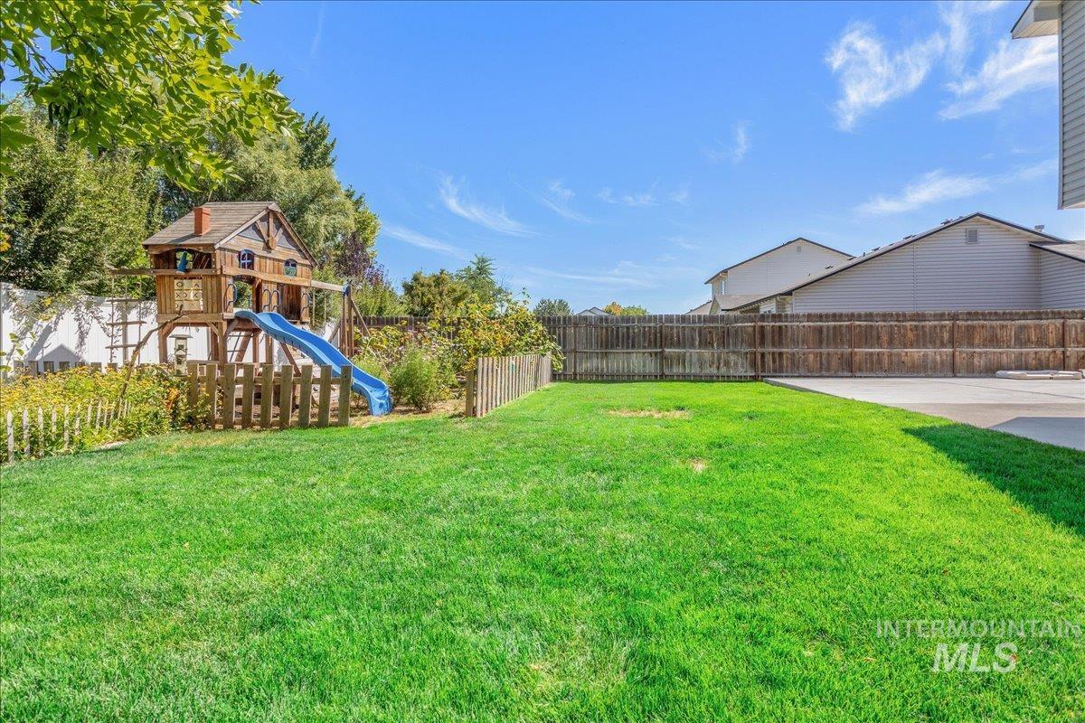 Fenced backyard featuring a playground