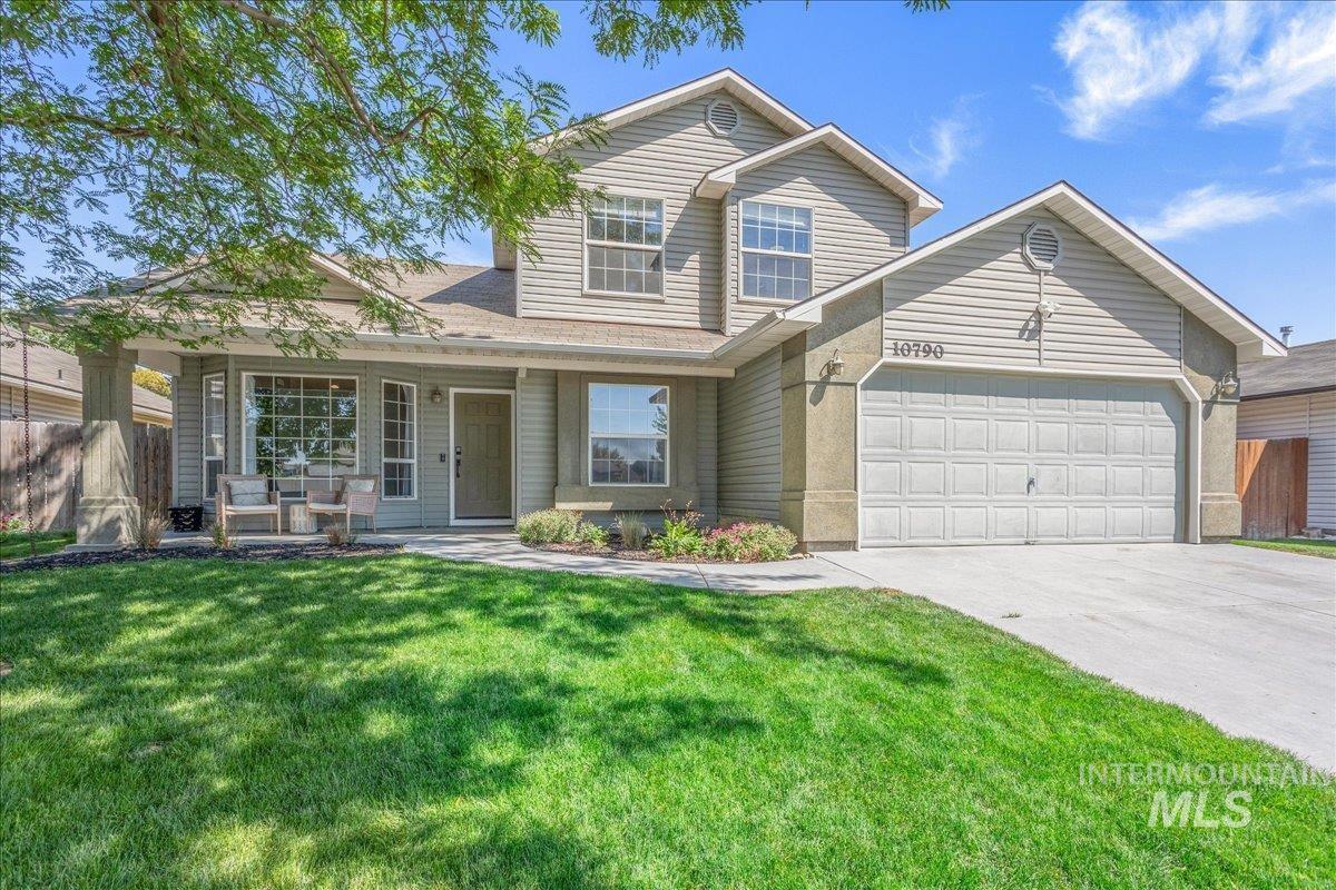 Traditional-style house featuring an attached garage, driveway, covered porch, and a shingled roof