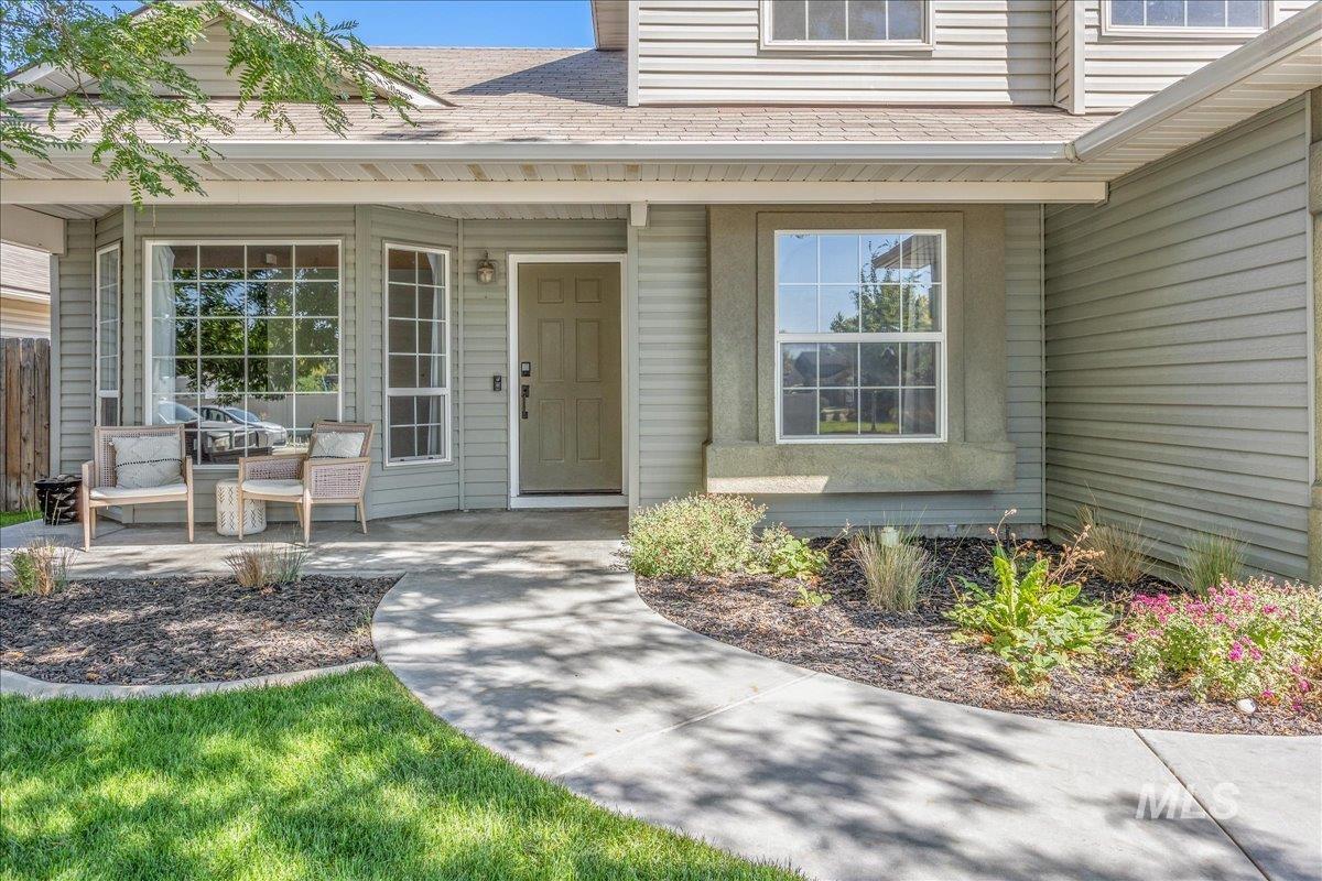Doorway to property with covered porch and a shingled roof