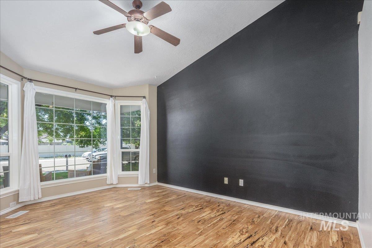 Empty room featuring lofted ceiling, light wood-style floors, and a ceiling fan