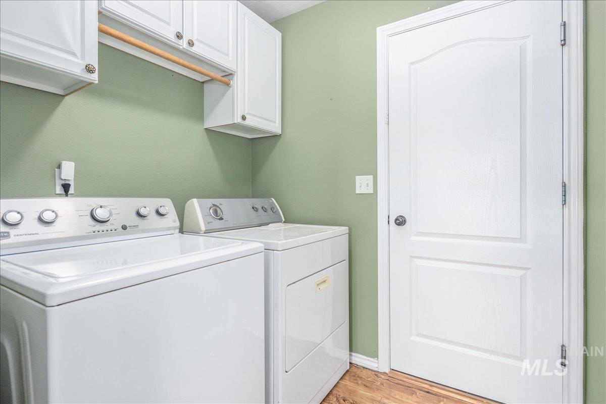 Laundry area featuring cabinet space, separate washer and dryer, and light wood finished floors