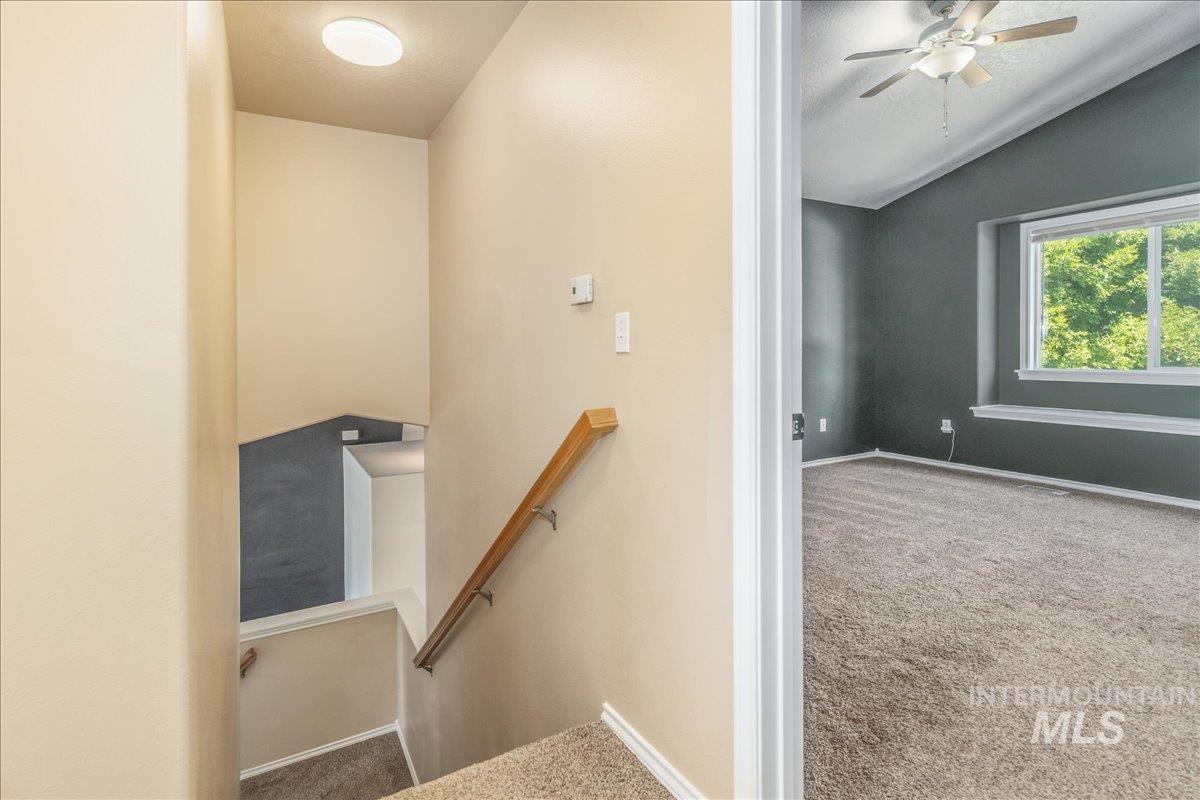 Stairway with carpet flooring, vaulted ceiling, a textured ceiling, and a ceiling fan