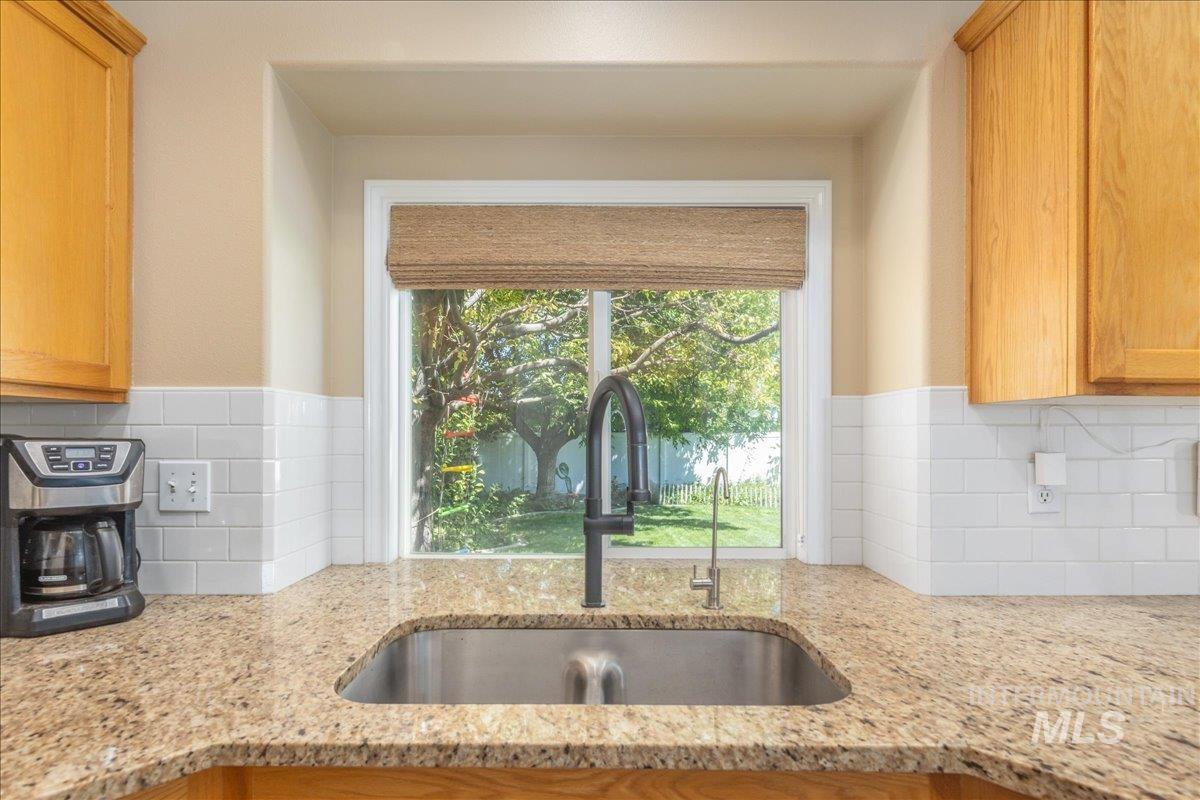 Kitchen featuring decorative backsplash, light stone countertops, and brown cabinets