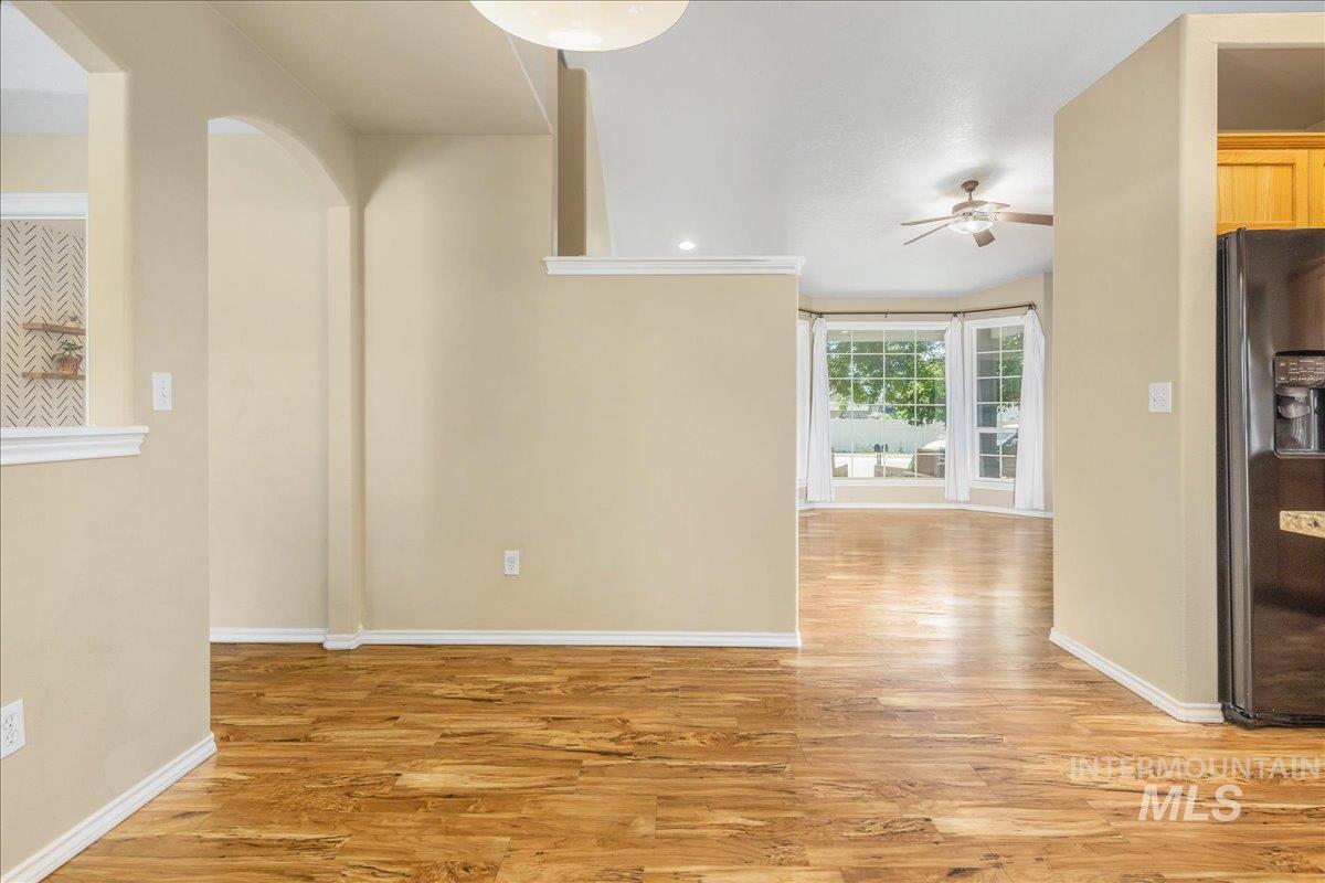 Unfurnished dining area featuring light wood finished floors, arched walkways, ceiling fan, and recessed lighting