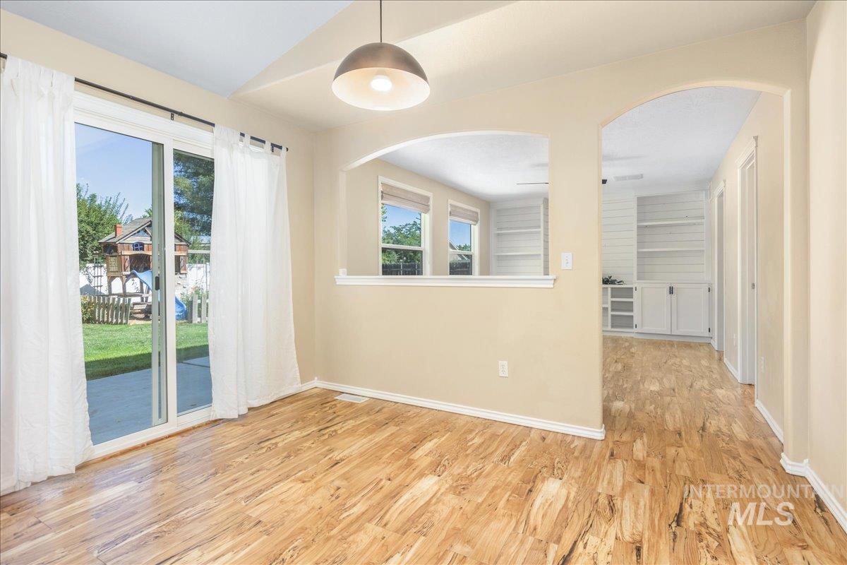 Spare room featuring light wood-type flooring, arched walkways, and vaulted ceiling