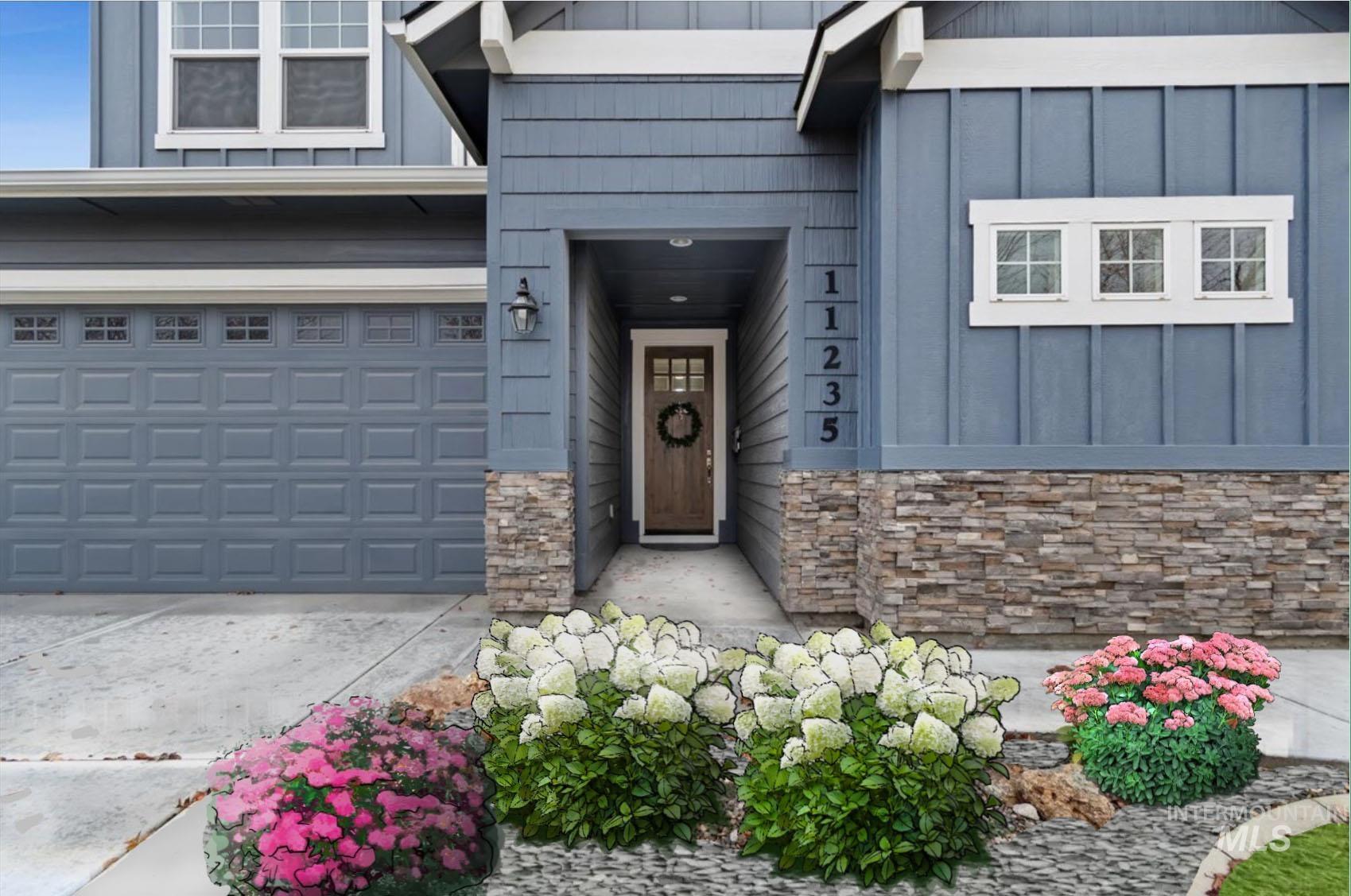 Entrance to property with board and batten siding, stone siding, concrete driveway, and a garage