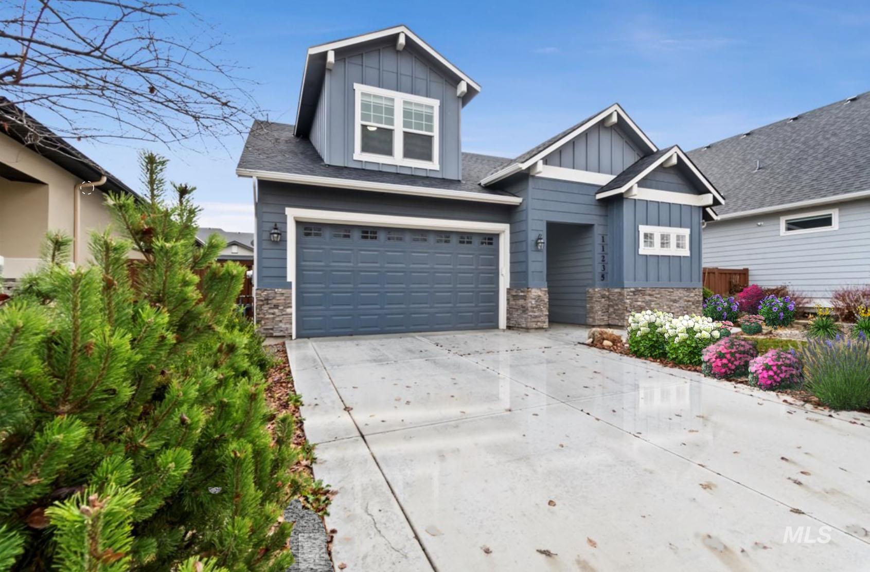 Craftsman-style home featuring board and batten siding, stone siding, concrete driveway, and a garage