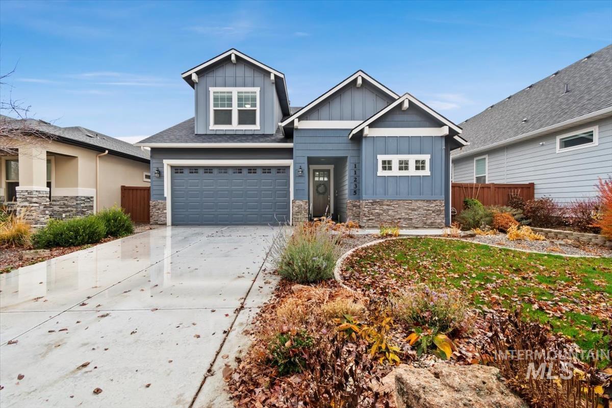 Craftsman inspired home featuring board and batten siding, stone siding, concrete driveway, and a garage