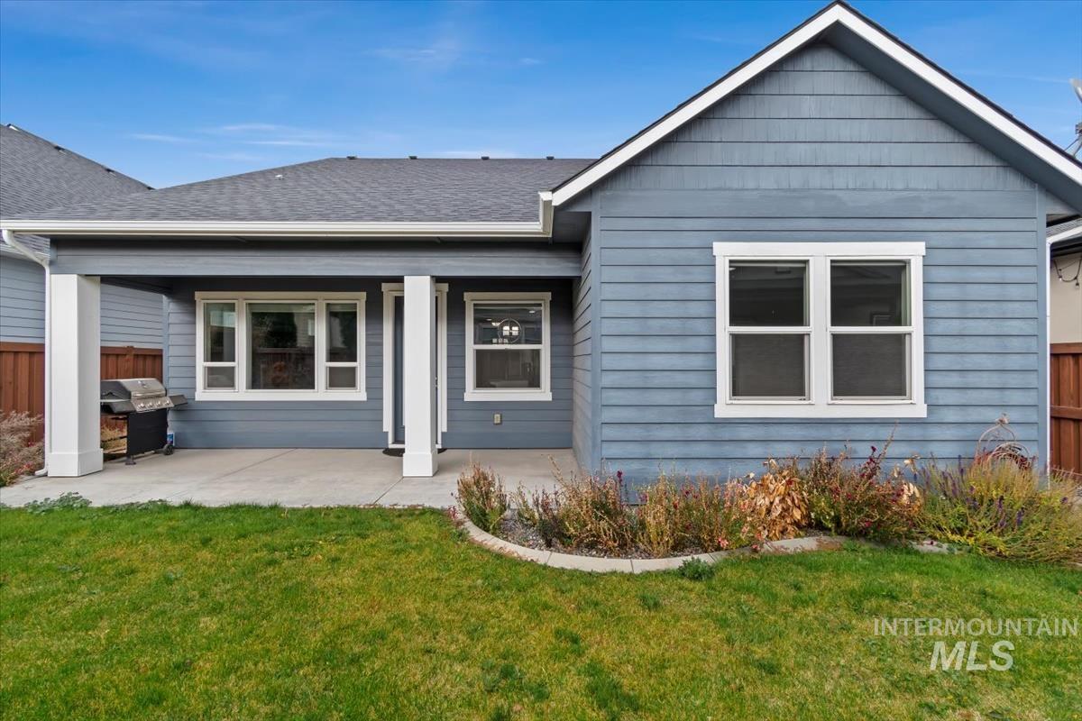 Rear view of house with roof with shingles and a patio area