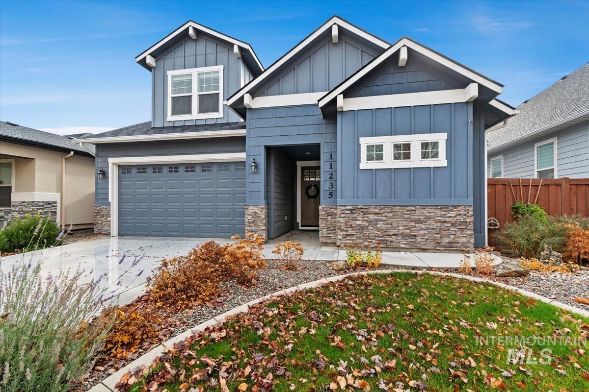Craftsman inspired home with board and batten siding, stone siding, driveway, and an attached garage