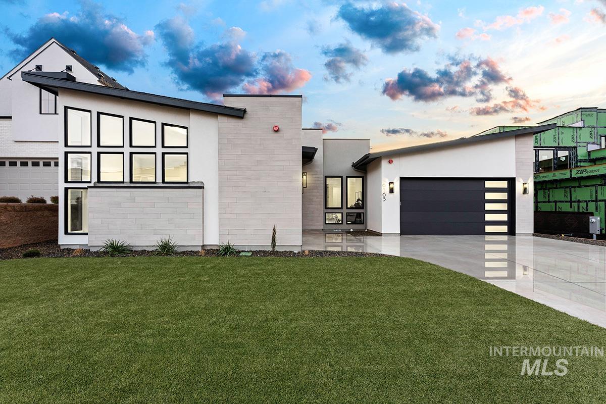 Modern home featuring a garage, stucco siding, concrete driveway, and a front lawn