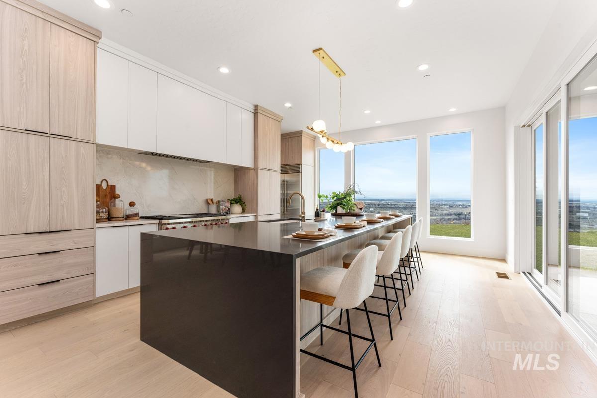 Two tone kitchen featuring a kitchen breakfast bar, two tone color scheme, light wood-type flooring, modern cabinets, and dark stone countertops