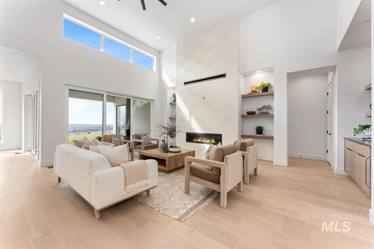 Living area with a high ceiling, built in shelves, light wood-type flooring, recessed lighting, and a ceiling fan