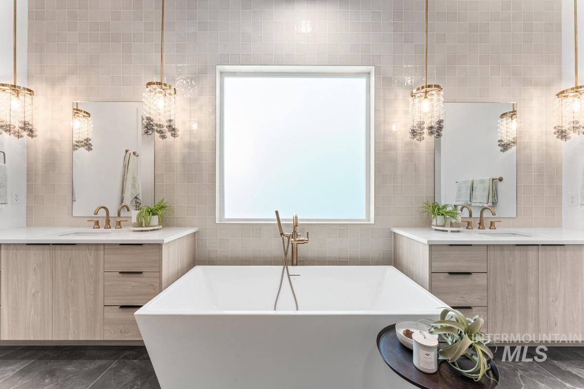 Bathroom with two vanities, tile walls, a freestanding tub, and backsplash