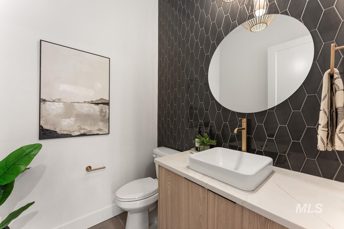 Half bathroom featuring vanity, tile walls, and decorative backsplash