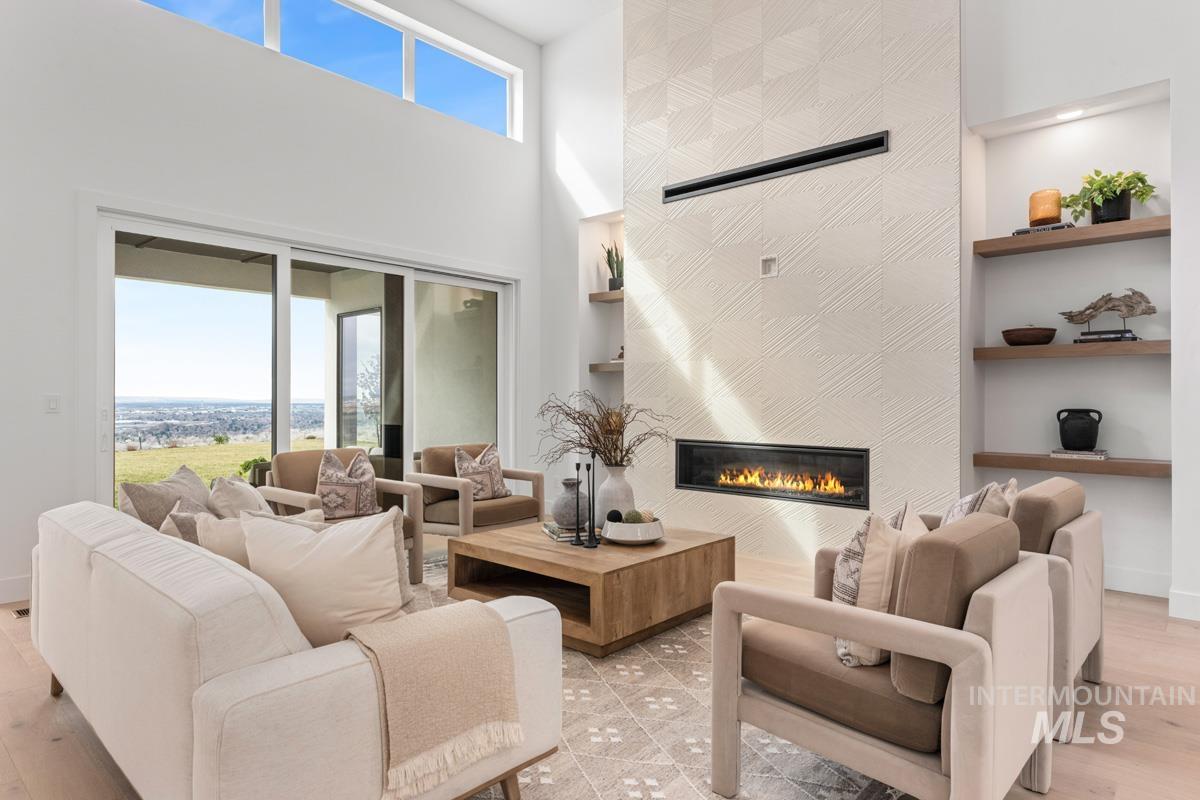 Living area with light wood-style flooring, built in features, a high ceiling, and plenty of natural light