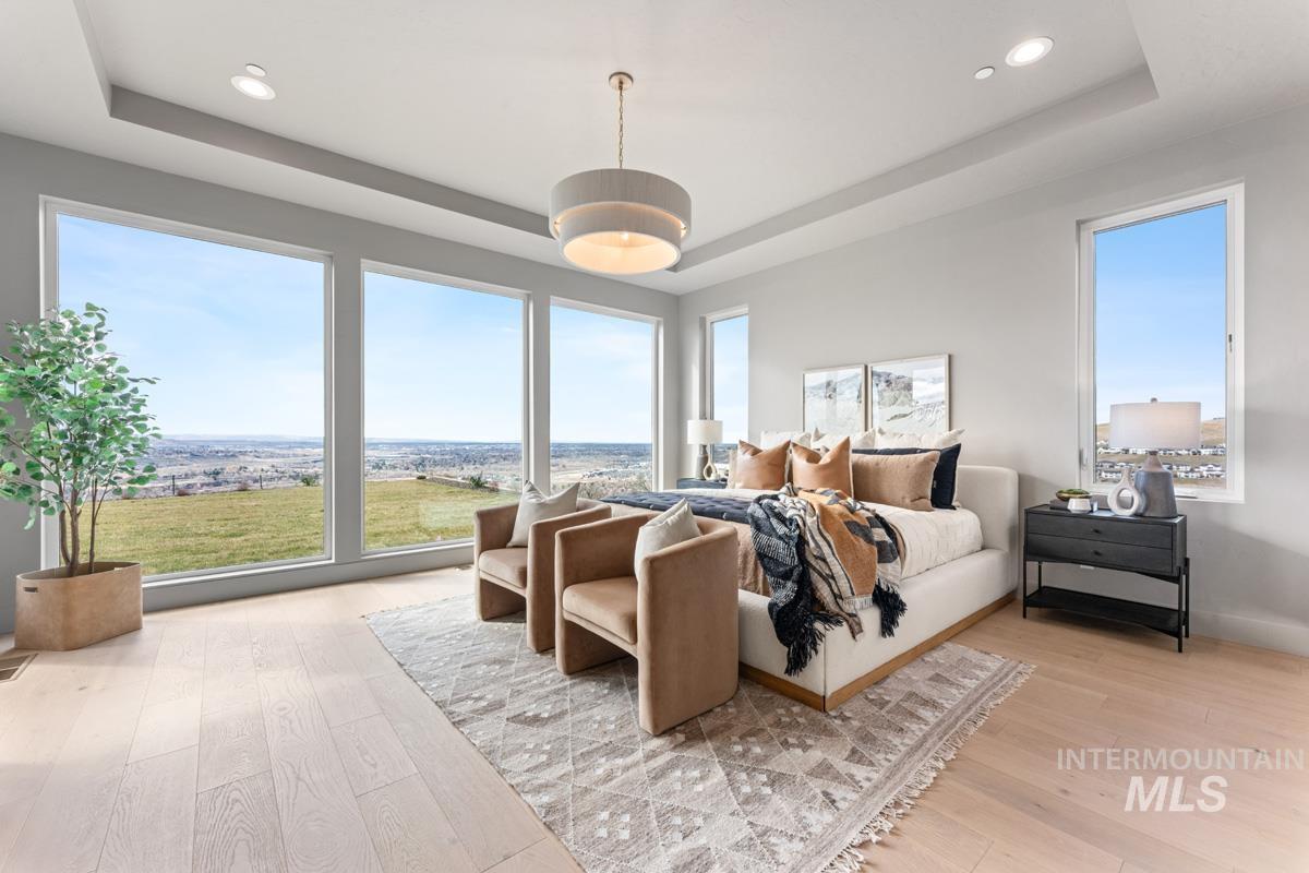 Bedroom with a raised ceiling, light wood-style flooring, and recessed lighting