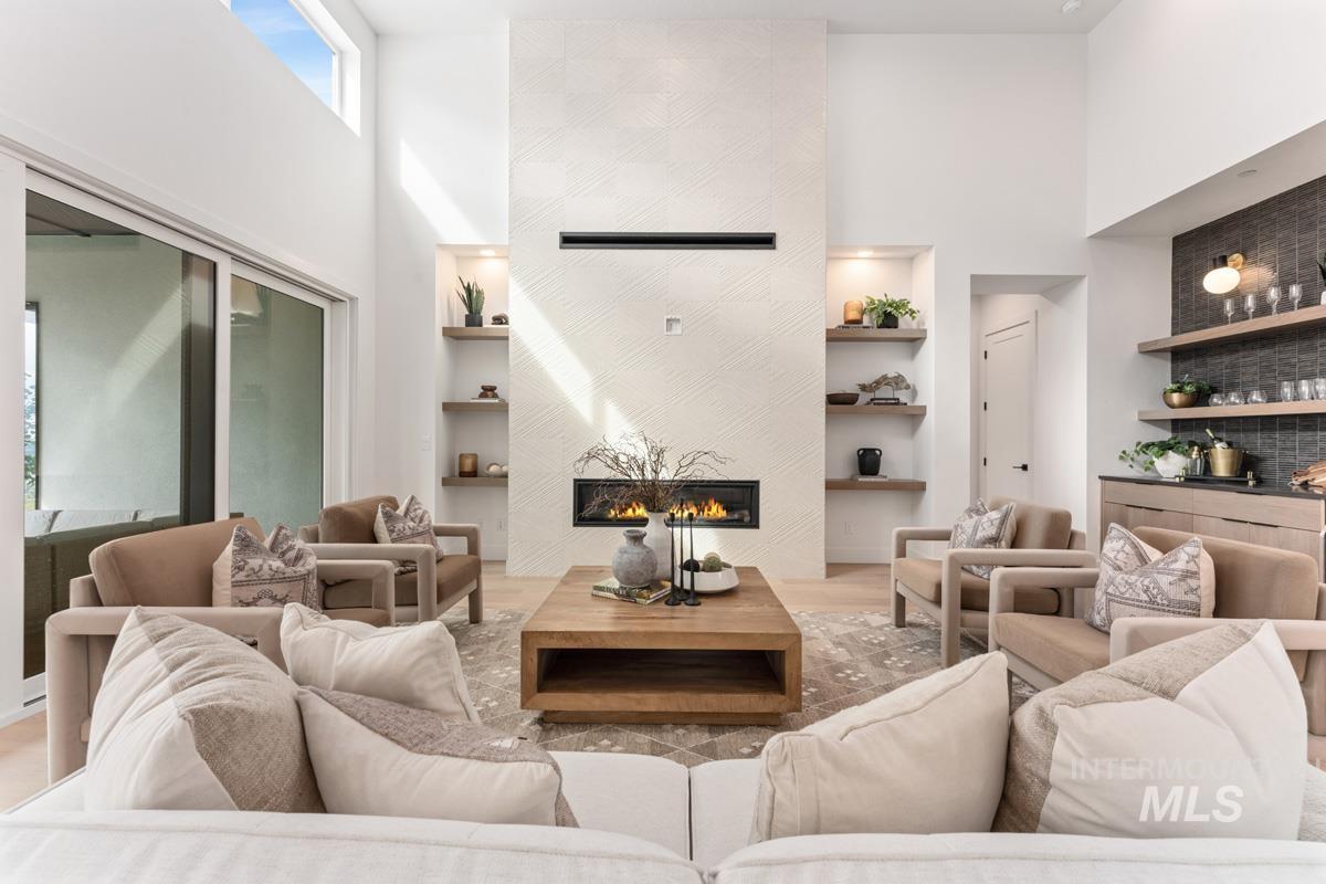 Living area featuring a high ceiling, wood finished floors, built in features, and a tiled fireplace