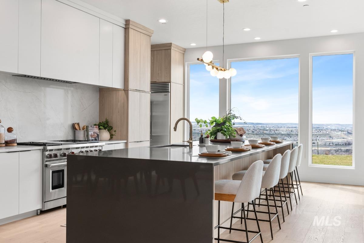 Two tone kitchen featuring modern cabinets, light wood-type flooring, high quality appliances, dual tone cabinetry, and a breakfast bar area