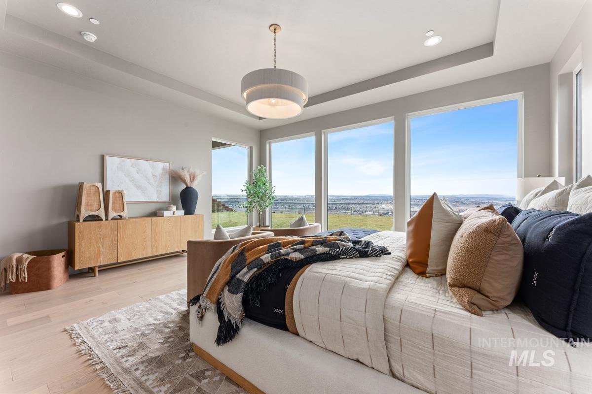 Bedroom with a raised ceiling, wood finished floors, and recessed lighting