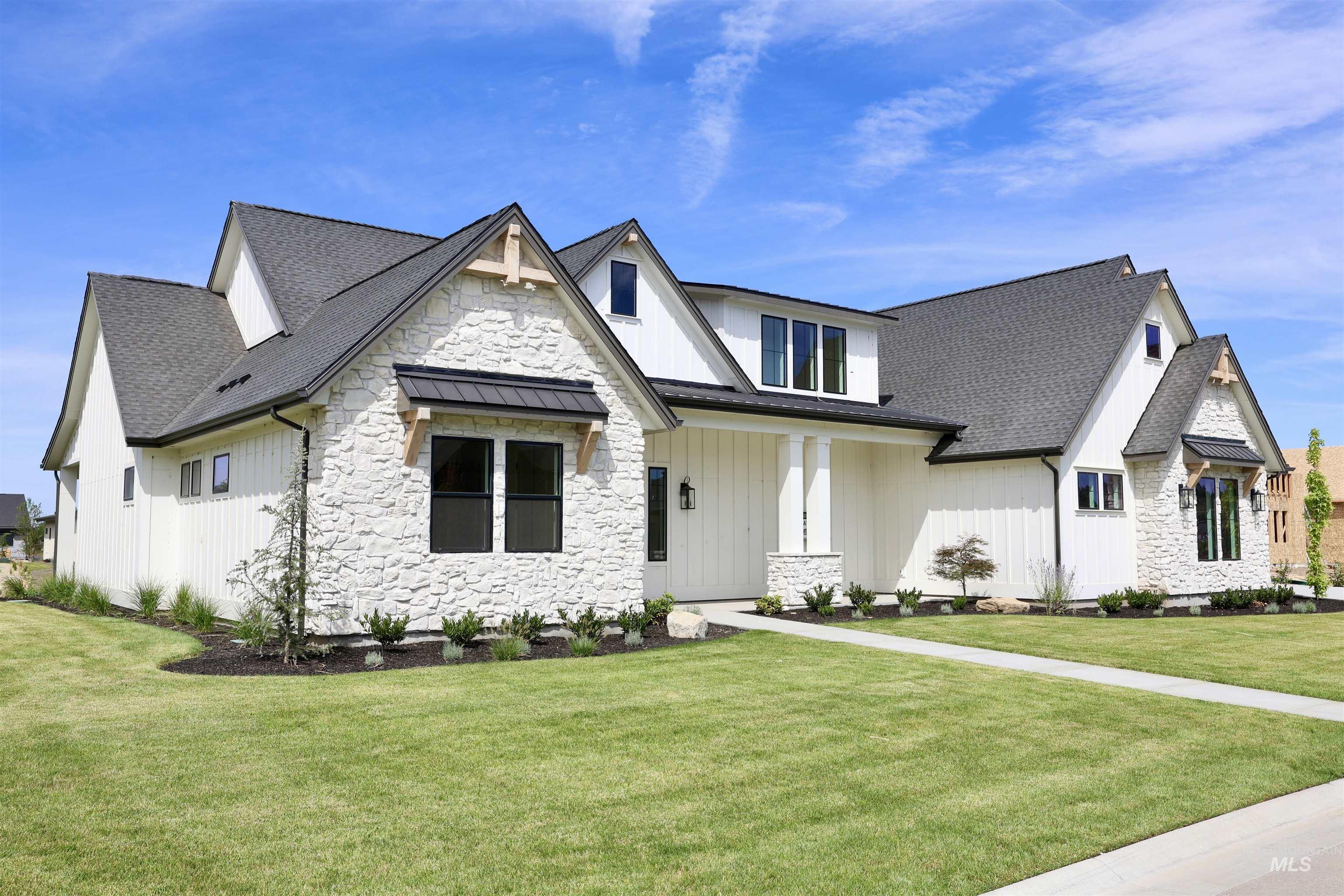 Modern farmhouse with stone siding, a shingled roof, a front yard, board and batten siding, and a standing seam roof