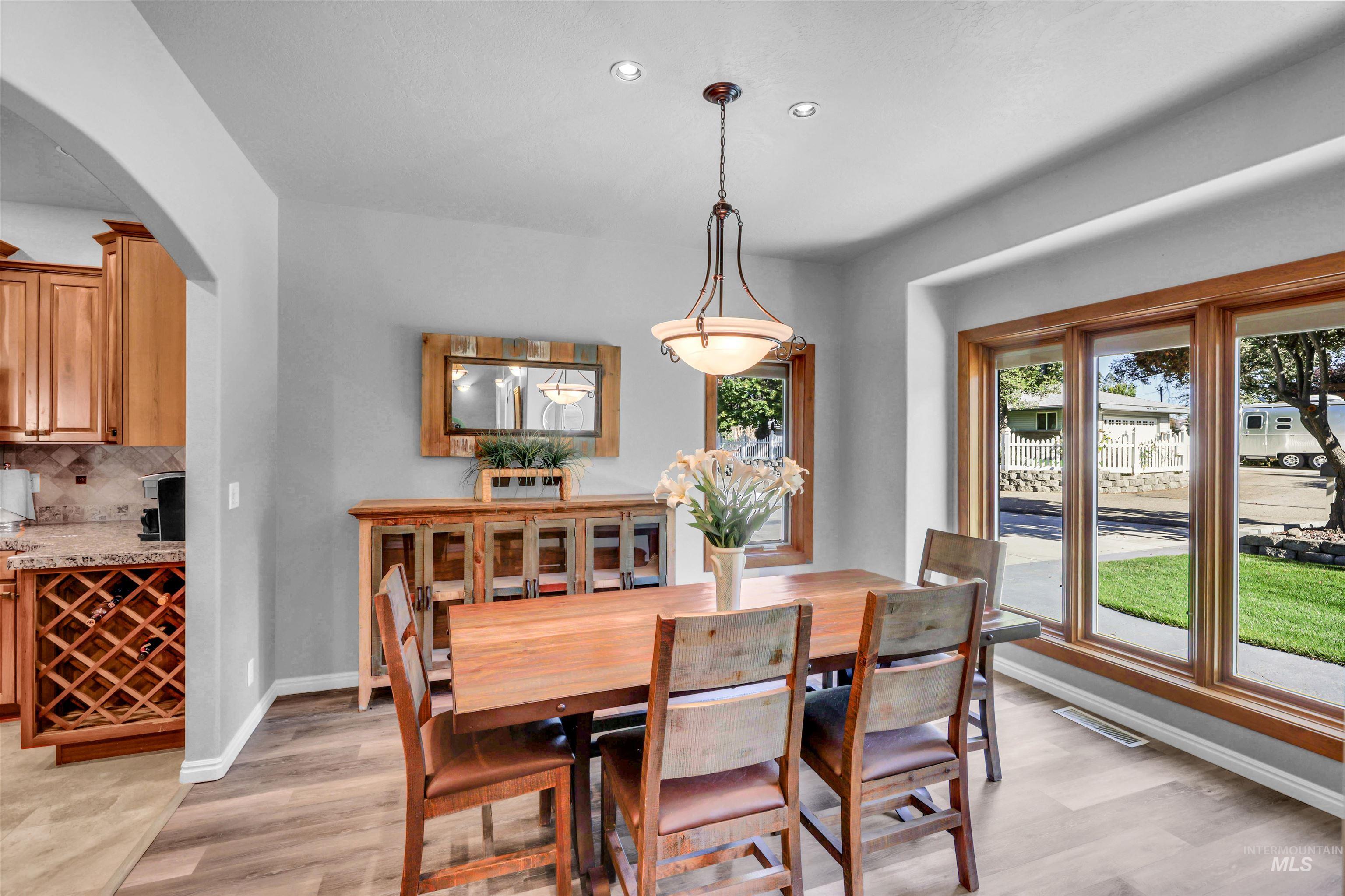 Dining space with arched walkways, light wood finished floors, and recessed lighting
