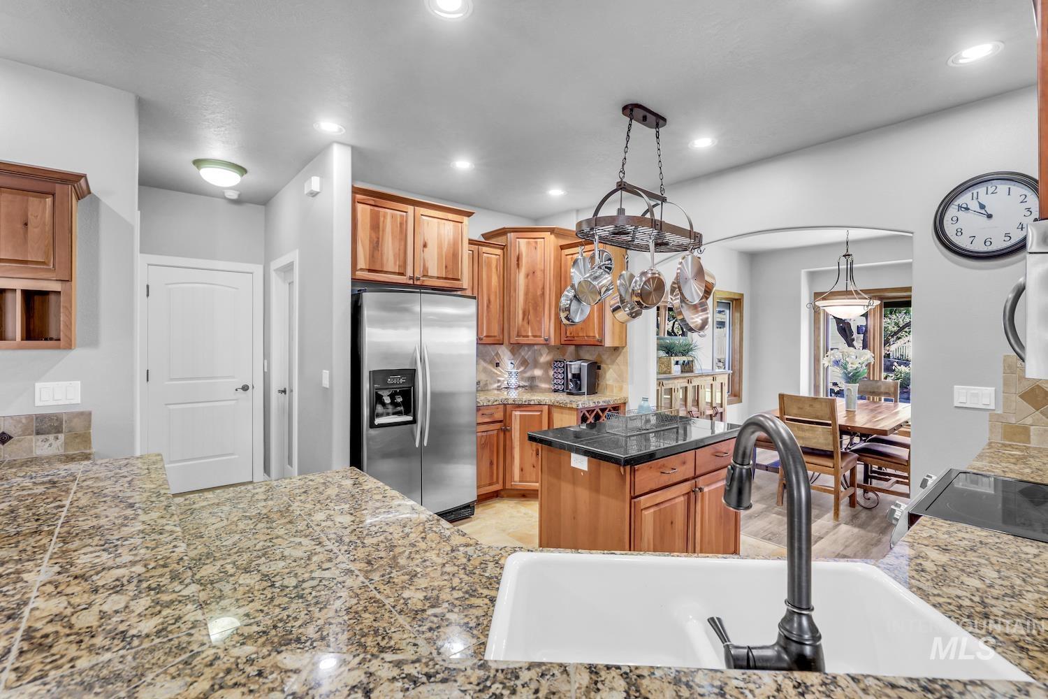 Kitchen with stainless steel refrigerator with ice dispenser, tile countertops, decorative backsplash, recessed lighting, and decorative light fixtures