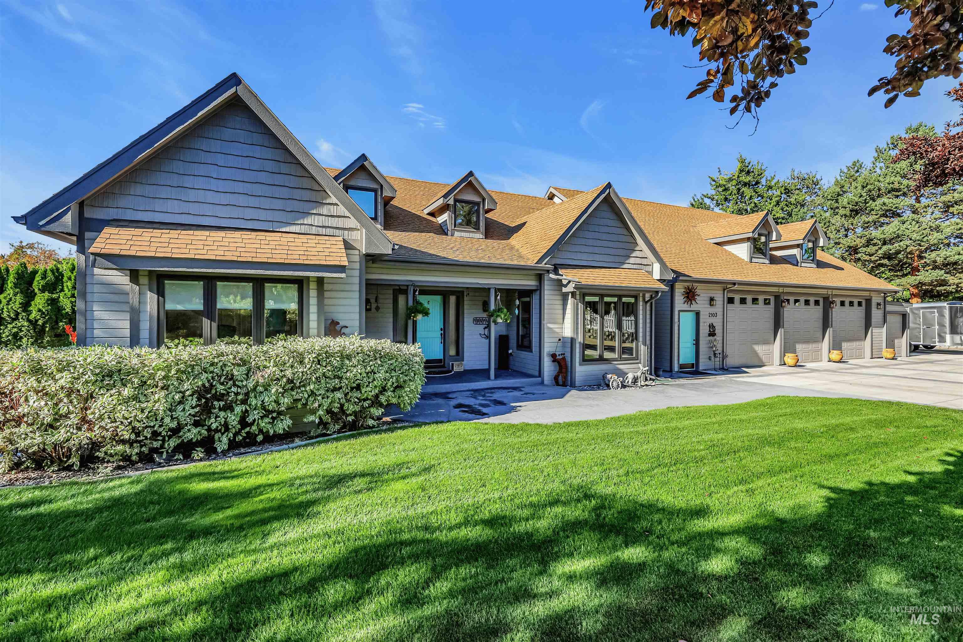 View of front of house with a front lawn, a shingled roof, covered porch, and driveway