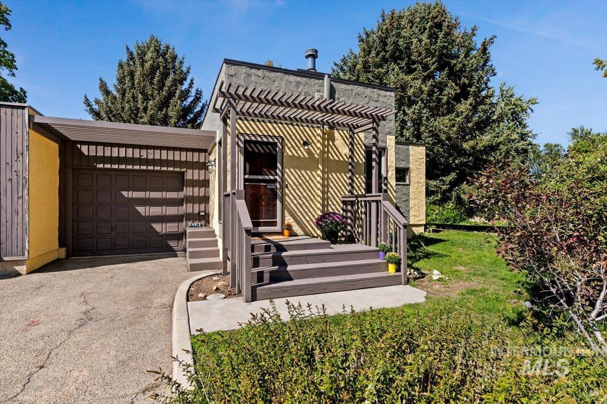 View of front of property featuring asphalt driveway, a garage, and a front lawn